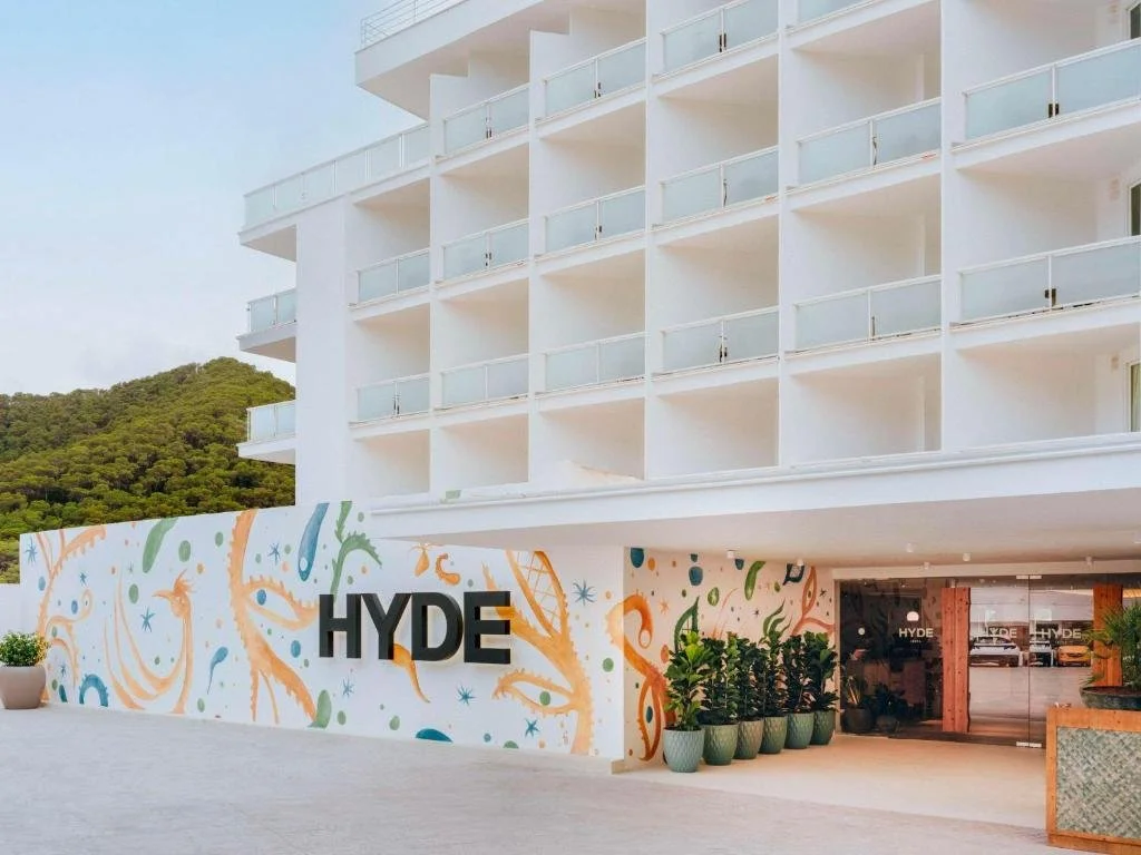 Modern hotel building with balconies and a colorful mural featuring abstract art and the word 'HYDE' at the entrance.