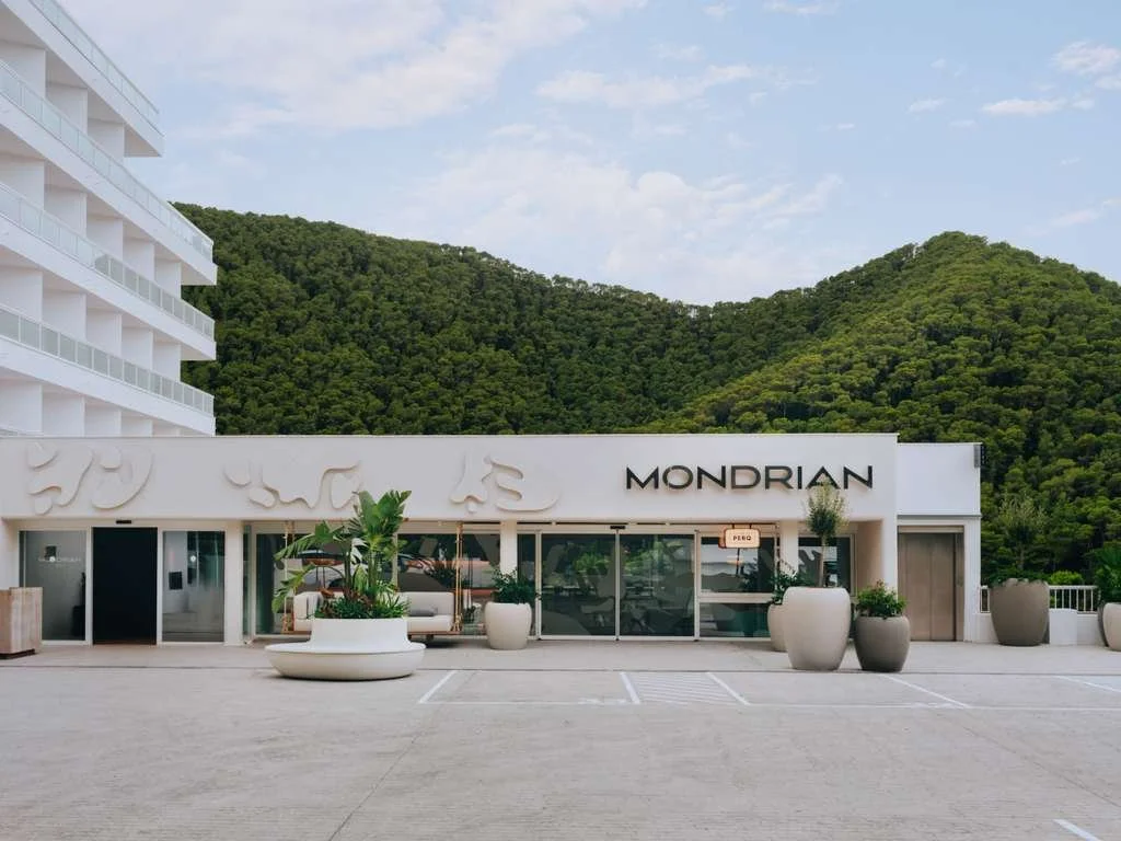Modern building with Mondrian sign in front of green hills