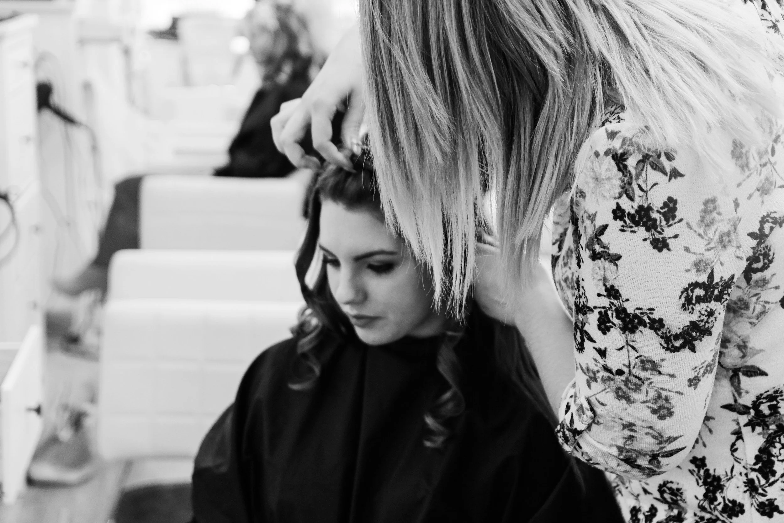 Hairdresser styling woman's hair in salon, black and white photo