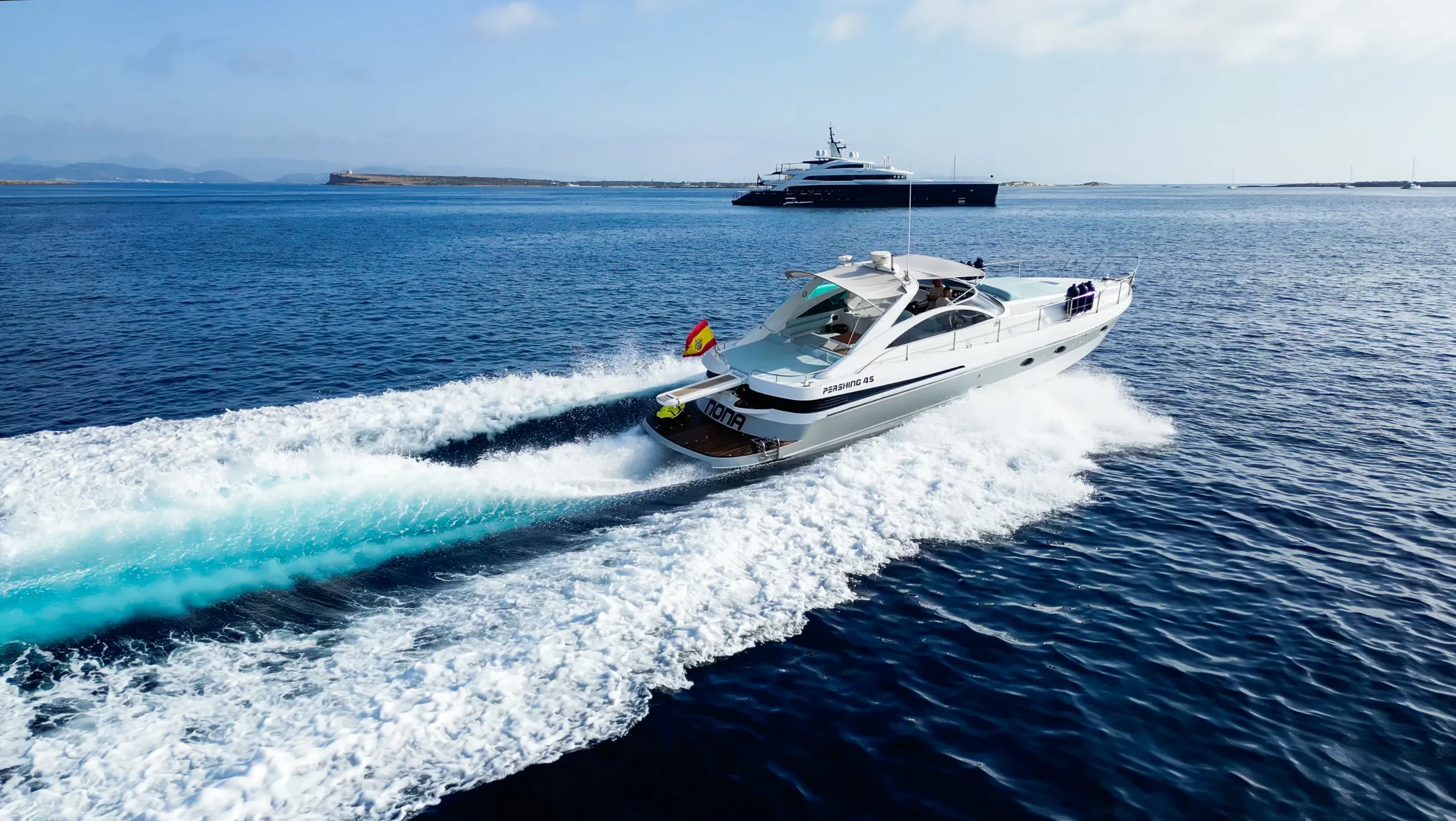 Pershing 45 Nona cruising fast with wake behind while exploring the Ibiza coastline
