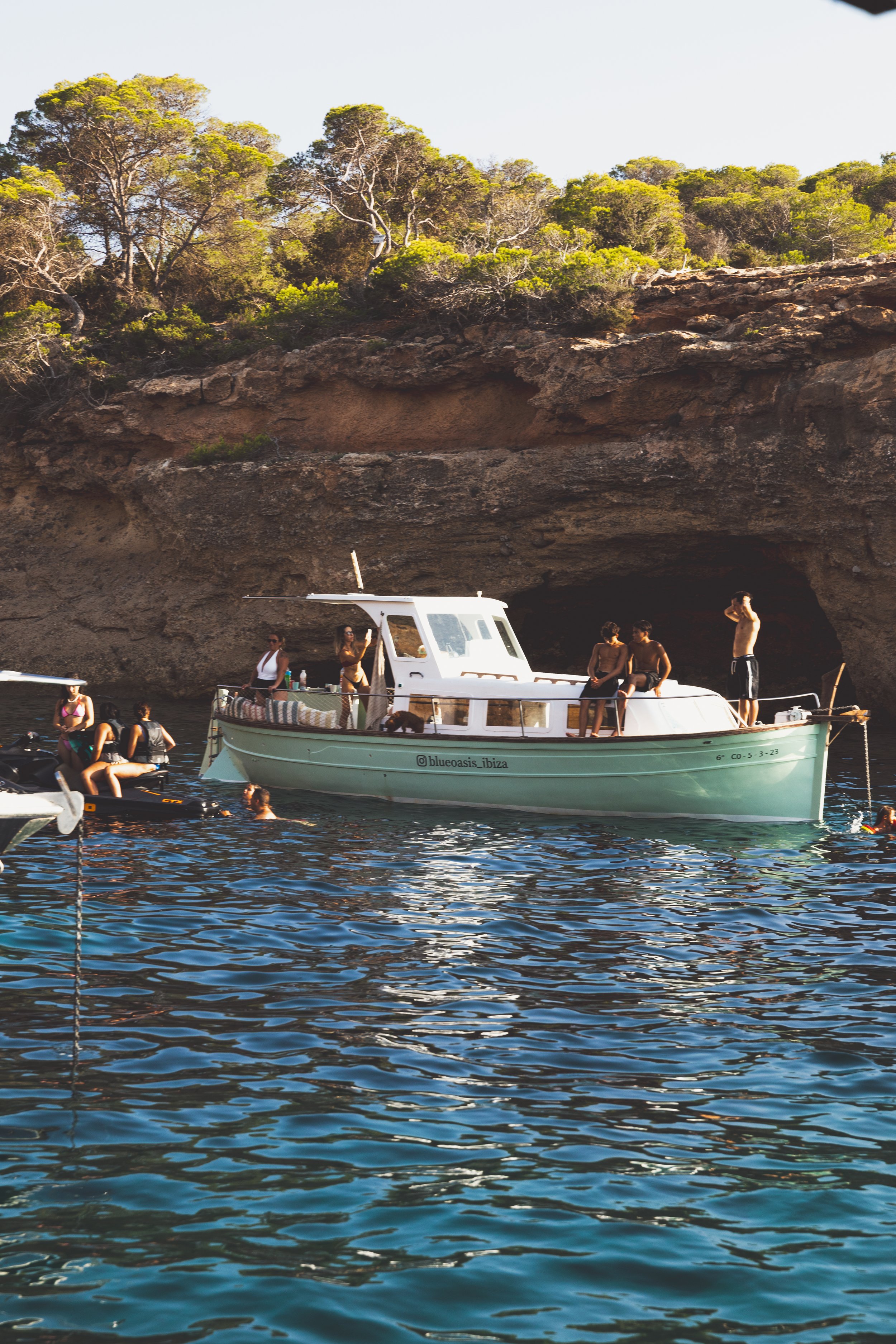 People on a boat near rocky shoreline.