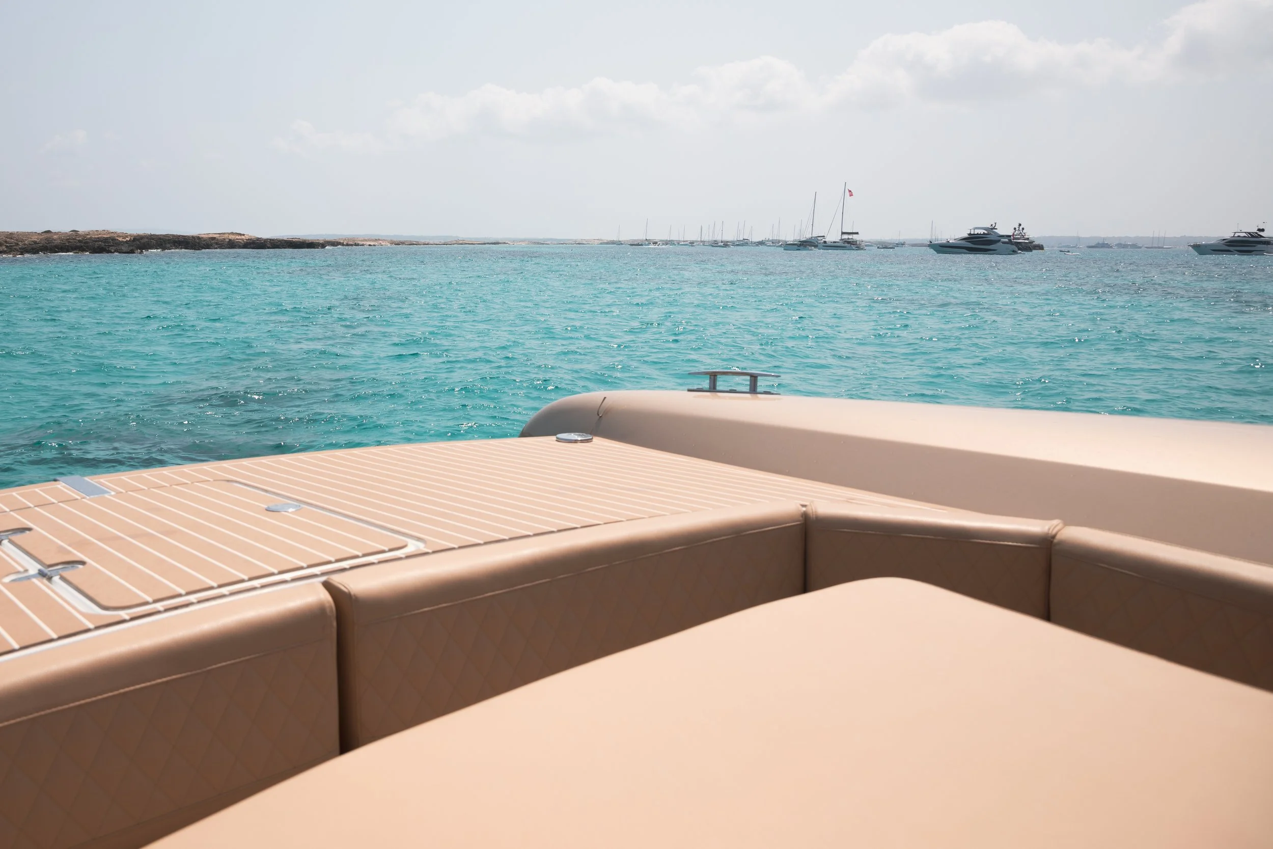 view from yacht deck over turquoise ocean with boats in distance