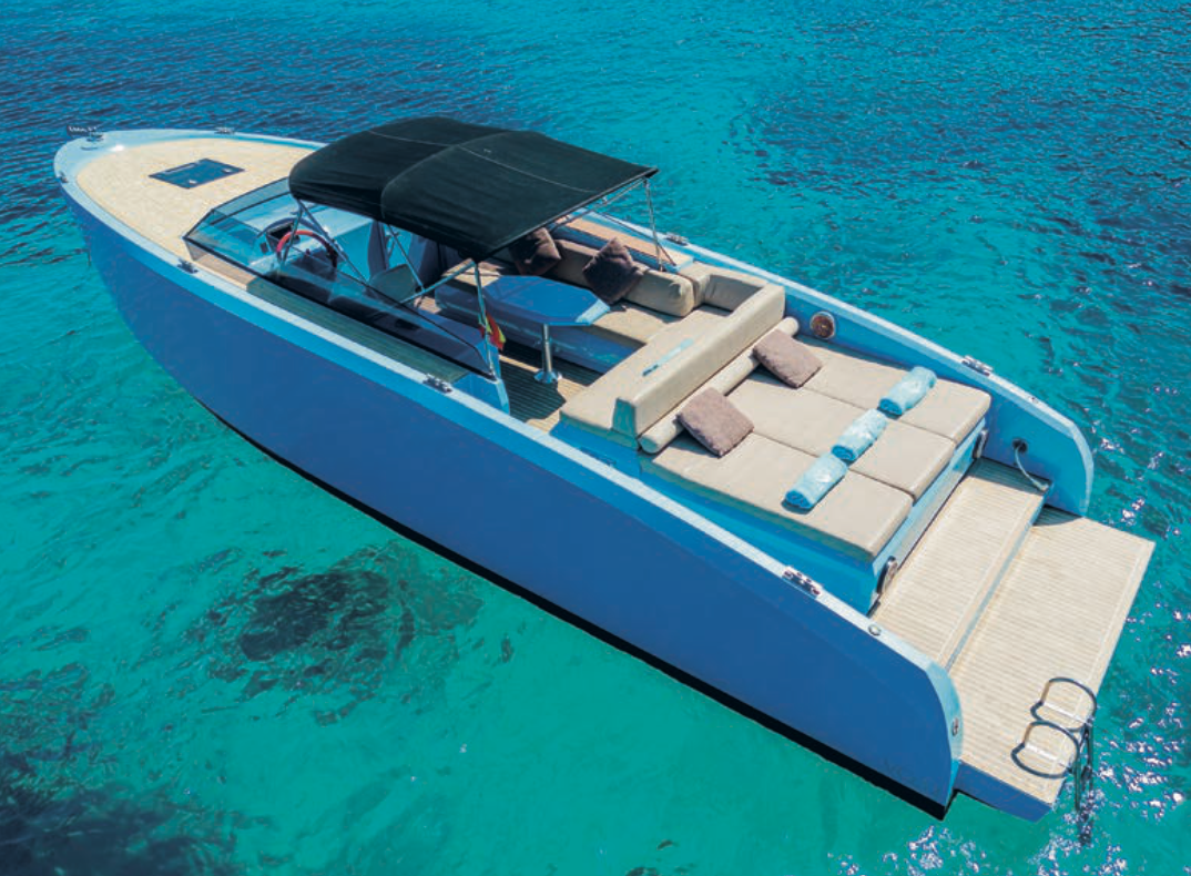 Luxury motorboat on clear blue water with sunbeds and canopy.