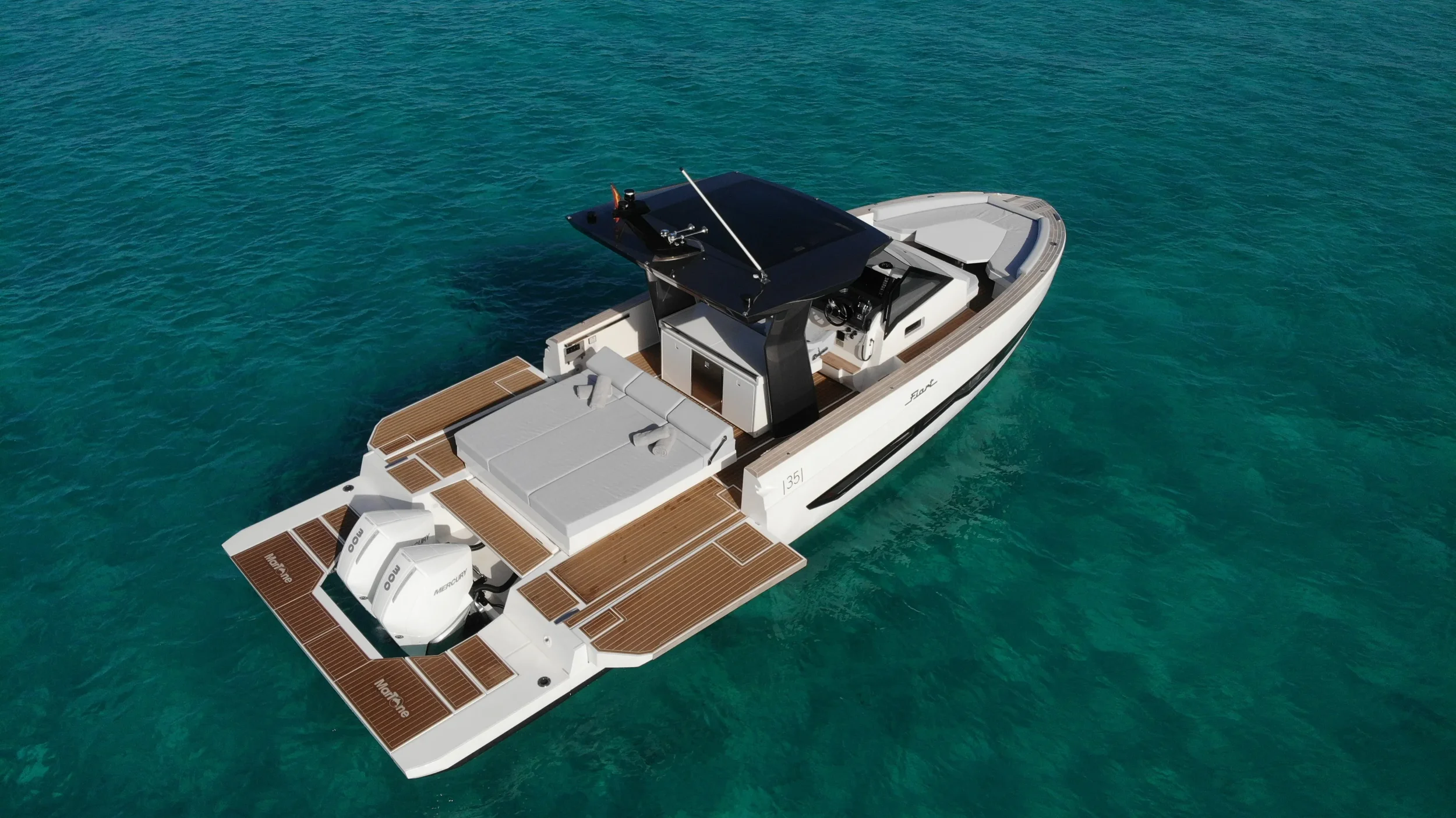Top-down view of the Fiart 35 Martone W with the stern terraces open and the white deck clearly visible over shallow turquoise sea.