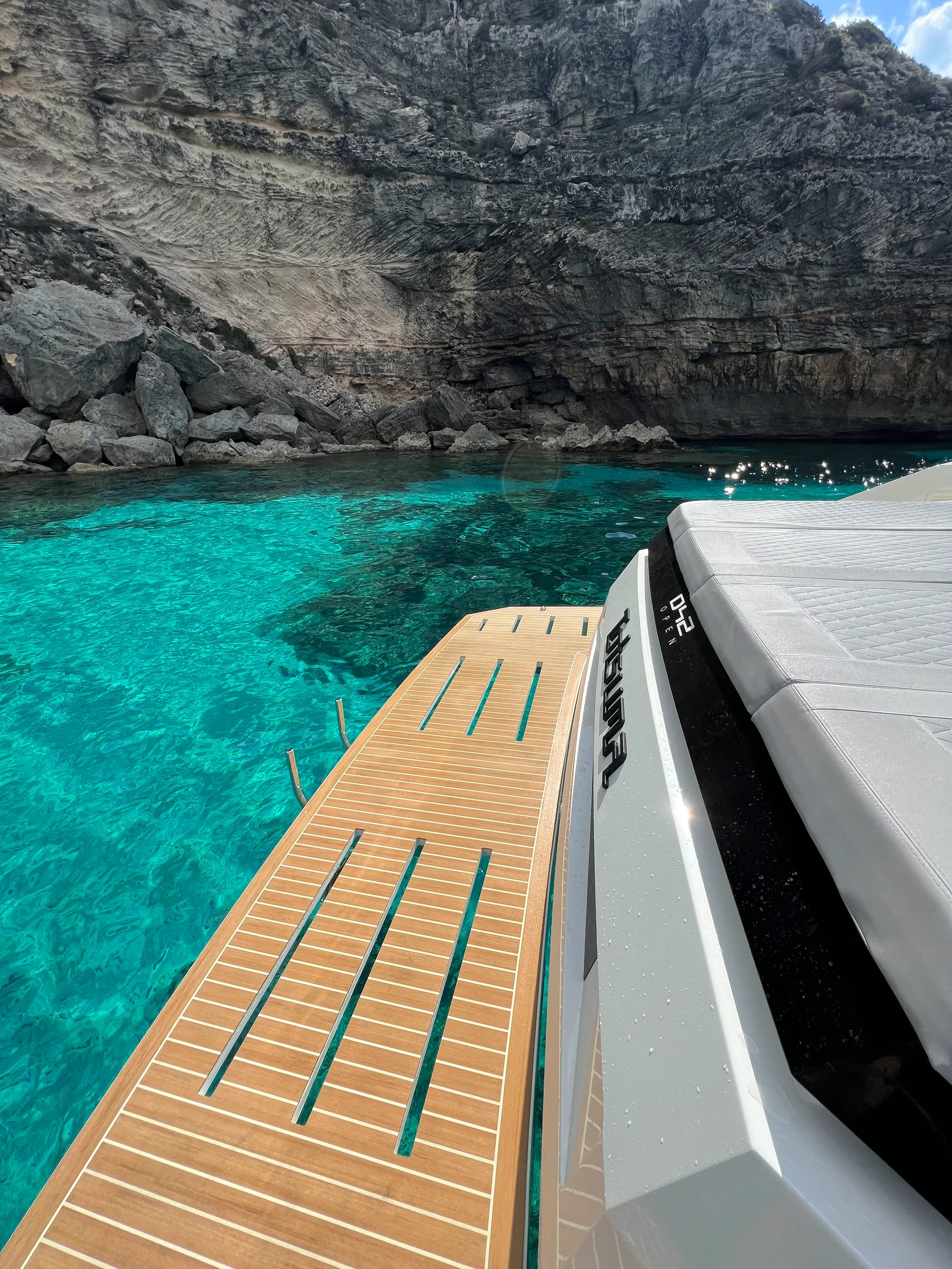 De Antonio 42 Tot Suma with its swim platform extended above bright blue water.