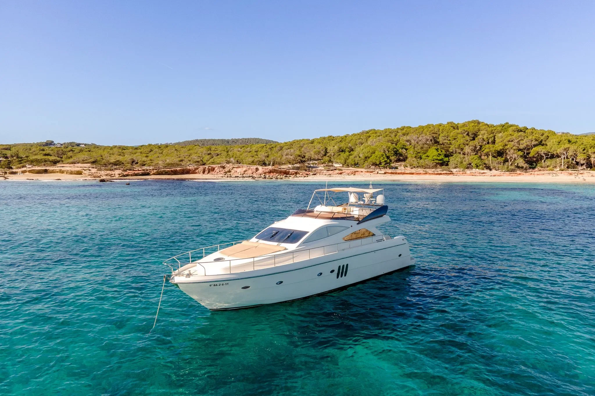 Abacus 61 Estela anchored near a quiet Ibiza cove with calm turquoise water