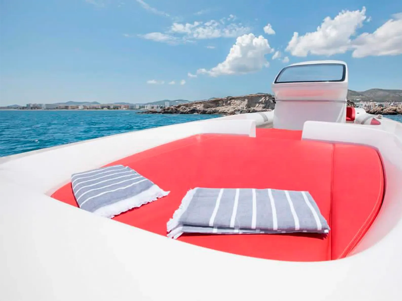 Front sunbed area of the Pirelli 1400 with red cushions and pillows under a blue Ibiza sky