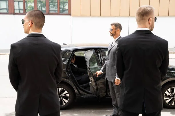 Bodyguards in suits standing by car with passenger