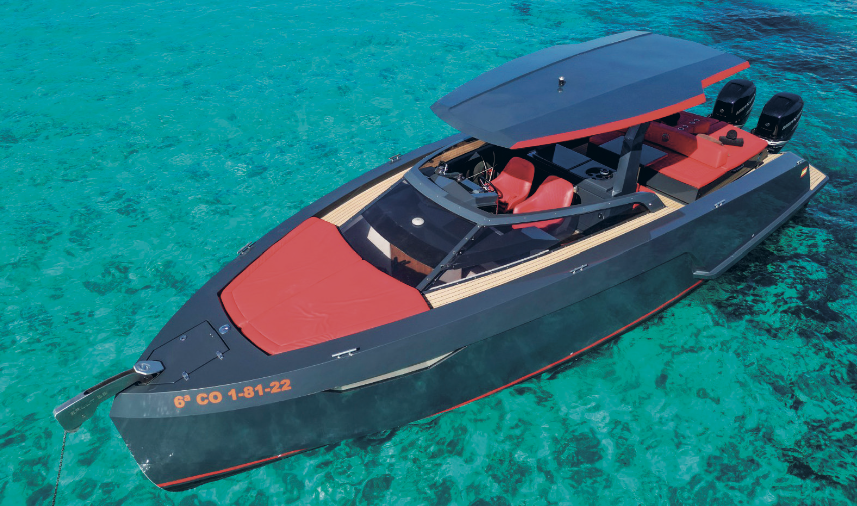 Luxury speedboat on clear turquoise water, featuring red seats and a dark sleek design.