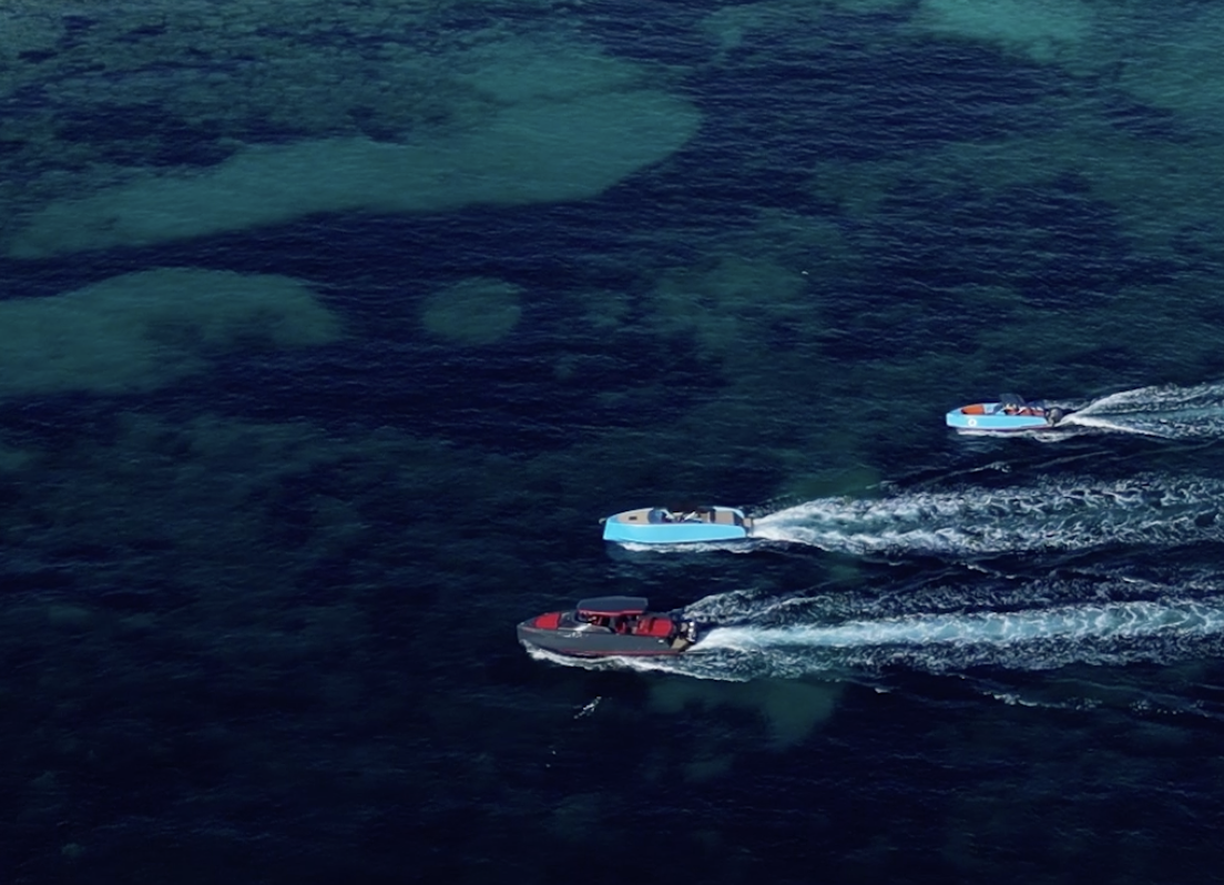 aerial view of three speedboats racing on clear blue ocean water