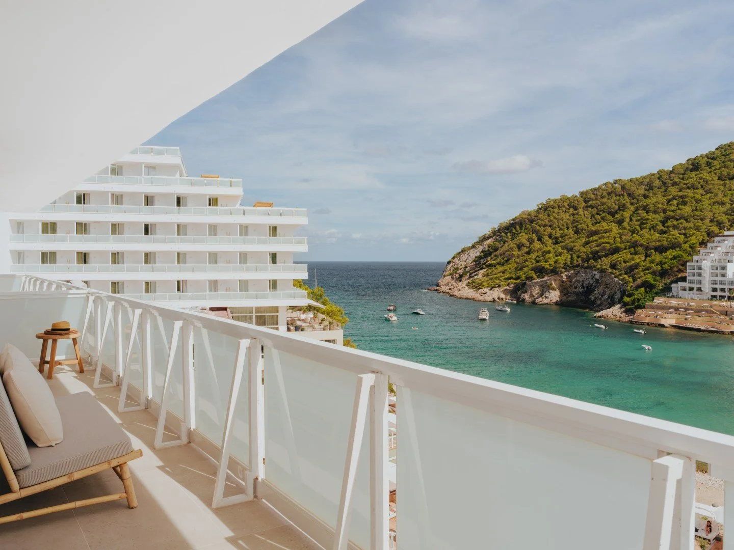 Coastal balcony view with ocean and hillside in the background.