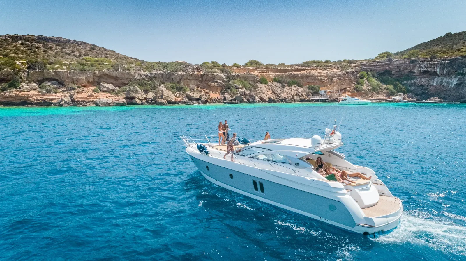 Sessa Marine 52 navigating close to the Ibiza coastline with open deck space and sun areas visible