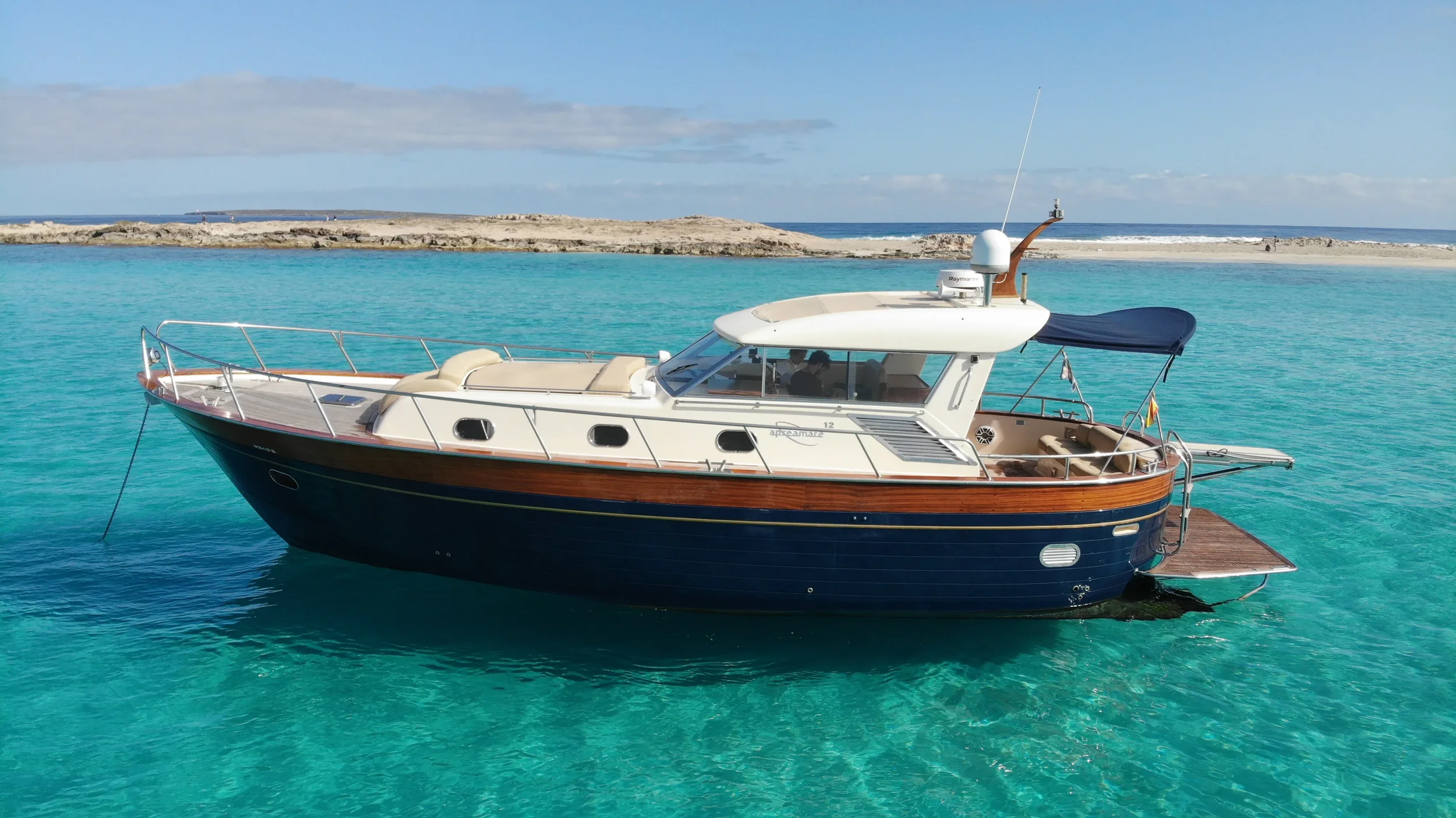 apreamare 45 scamp cruising near the coastline with its classic wooden lines reflecting on the water.