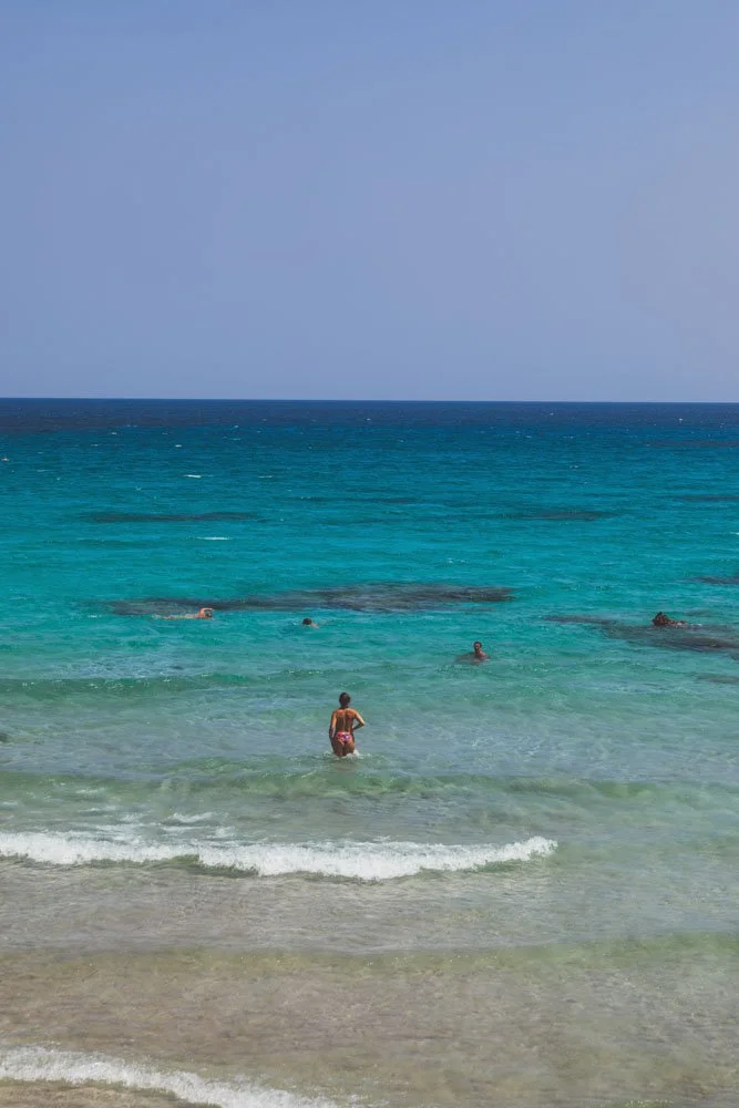 Beach with clear turquoise water and people swimming