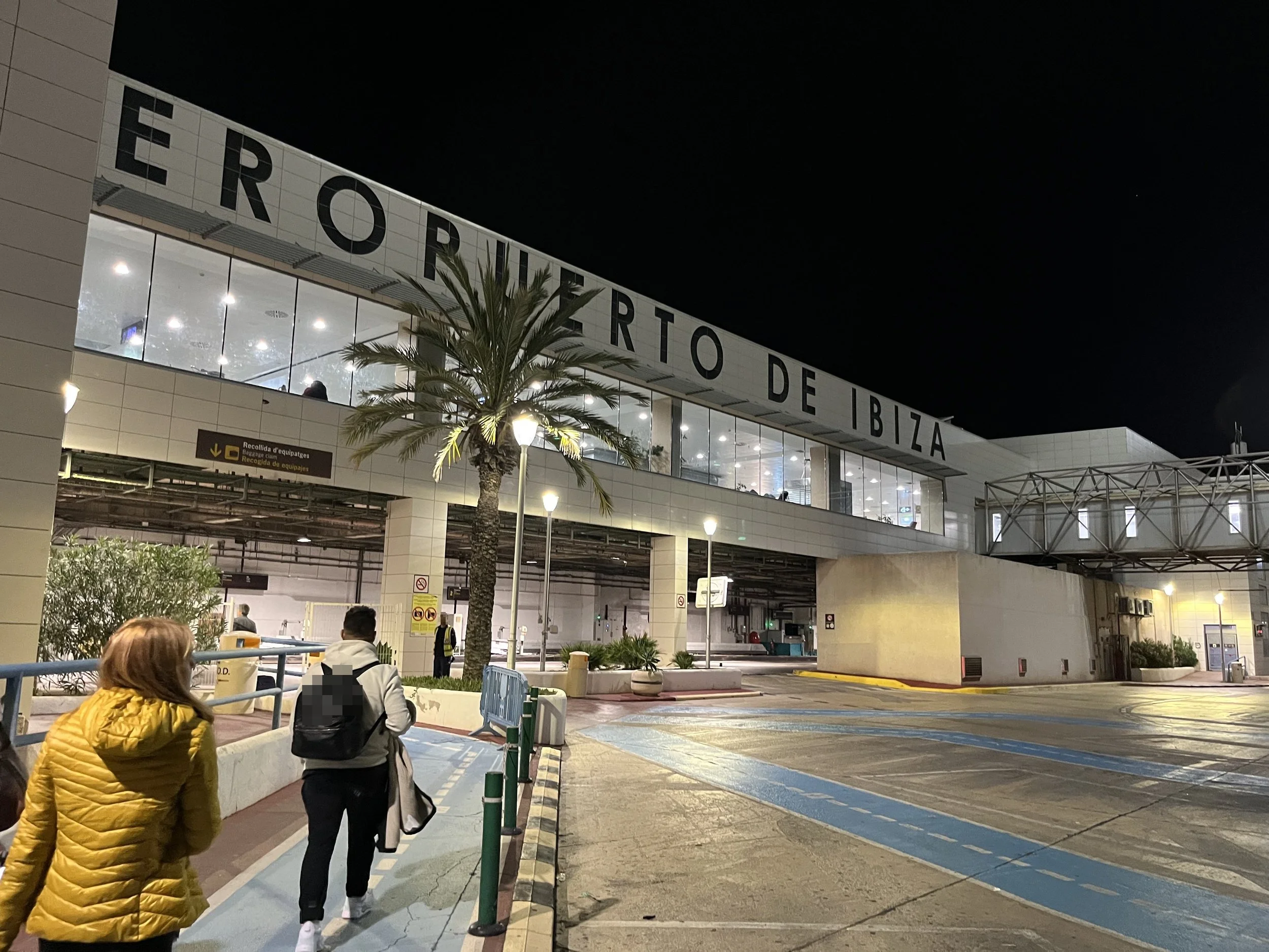 People walking towards Ibiza's airport entrance at night