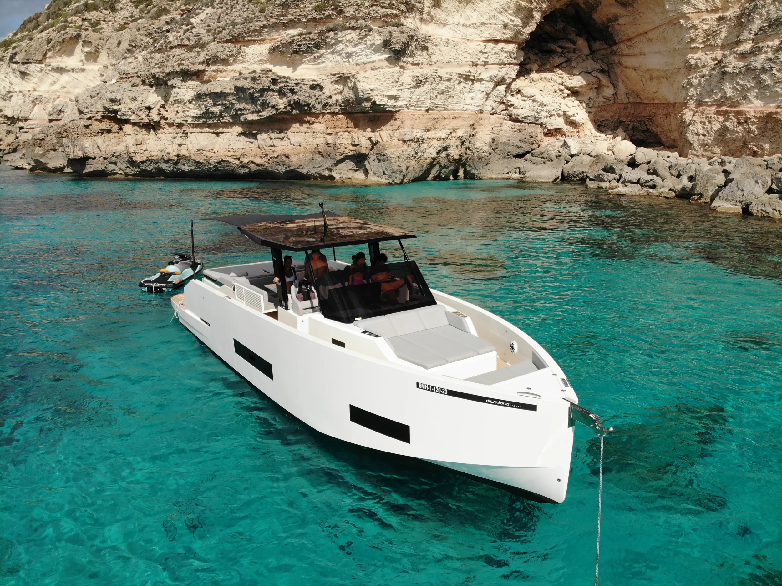 De Antonio 42 Tot Suma gliding calmly close to the coastline with soft sunlight on the bow.