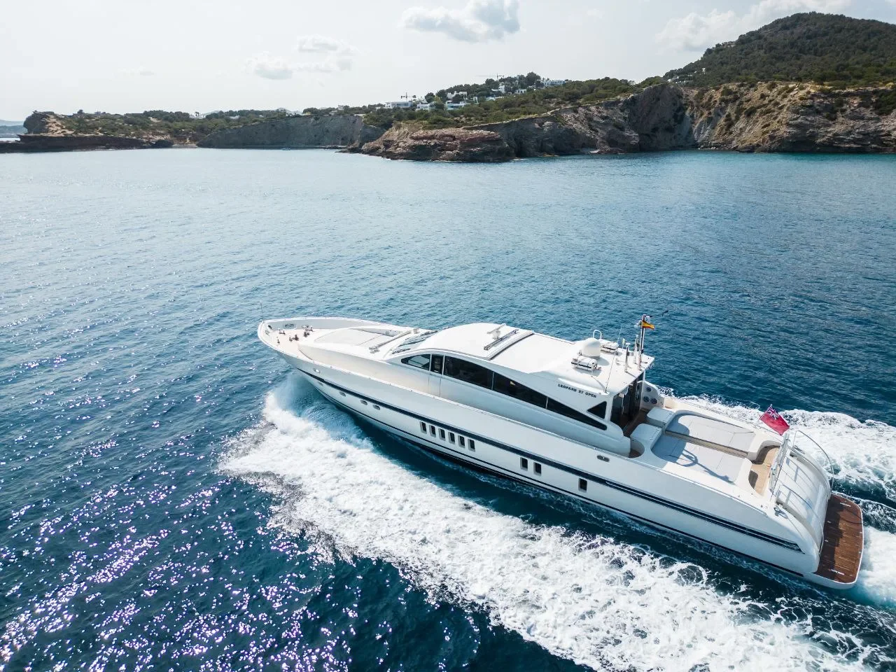 Leopard 27 Byron underway at speed creating a clean wake near rocky shoreline
