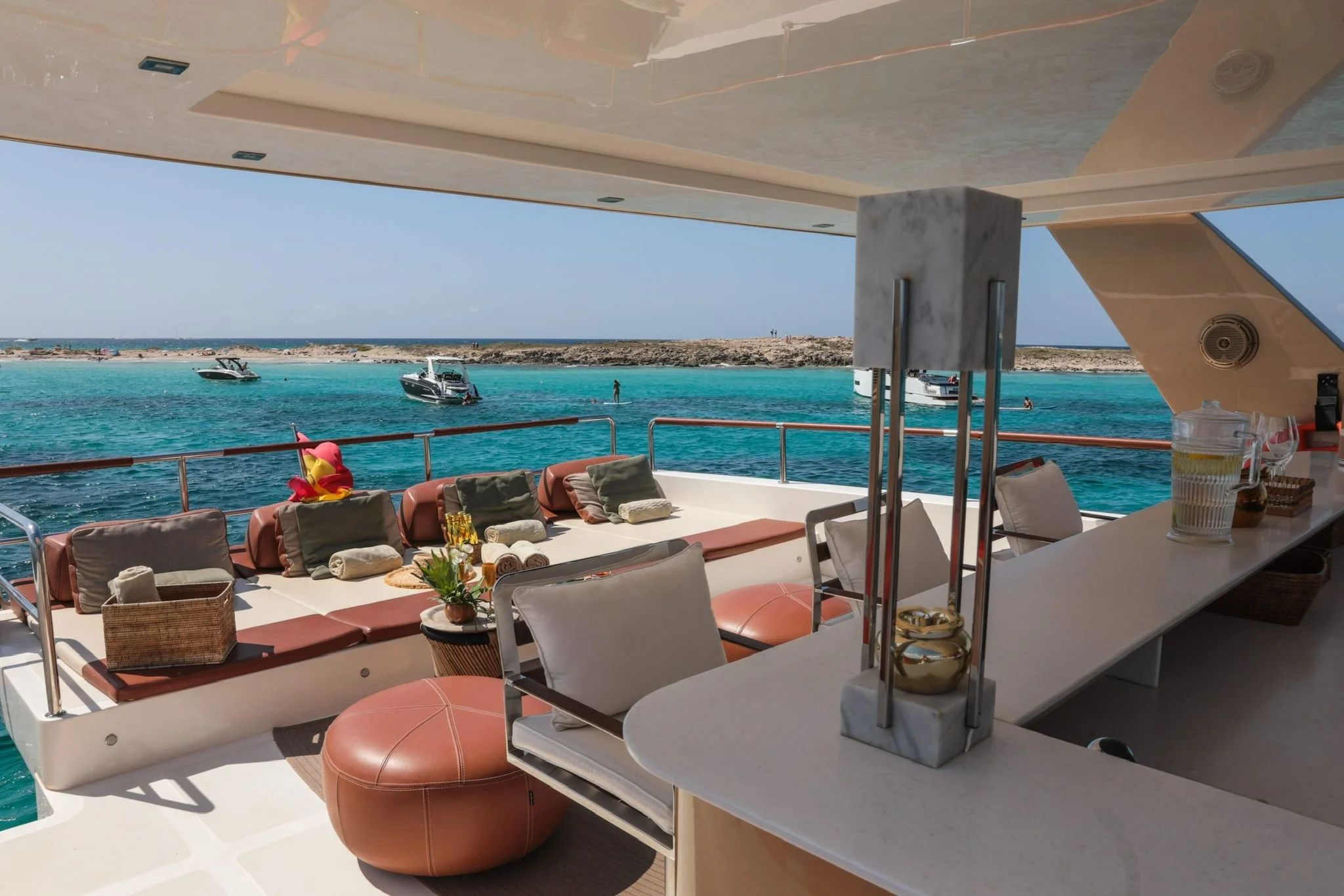 Luxury yacht deck with seating, table, ocean view, and nearby boats.