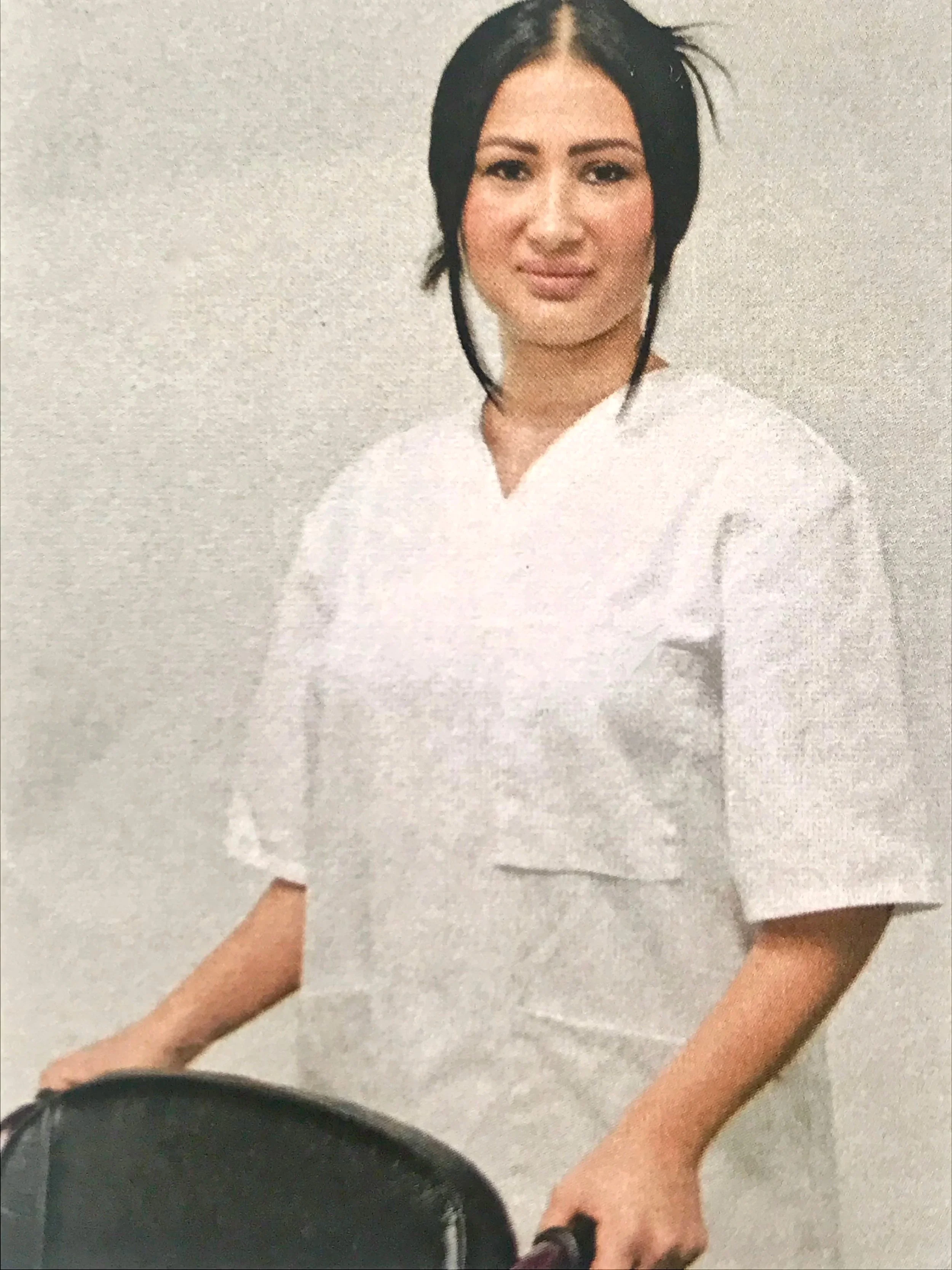 Frau in weißem medizinischem Kittel steht mit einem Rollstuhl