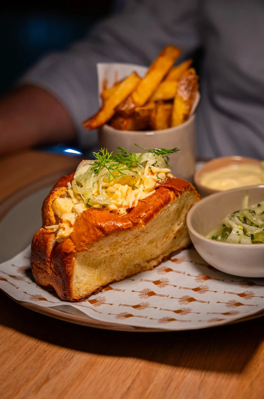 Lobster roll with dill and coleslaw, served with a side of fries and dipping sauce on a decorative plate at Naama restaurant in Marrakech