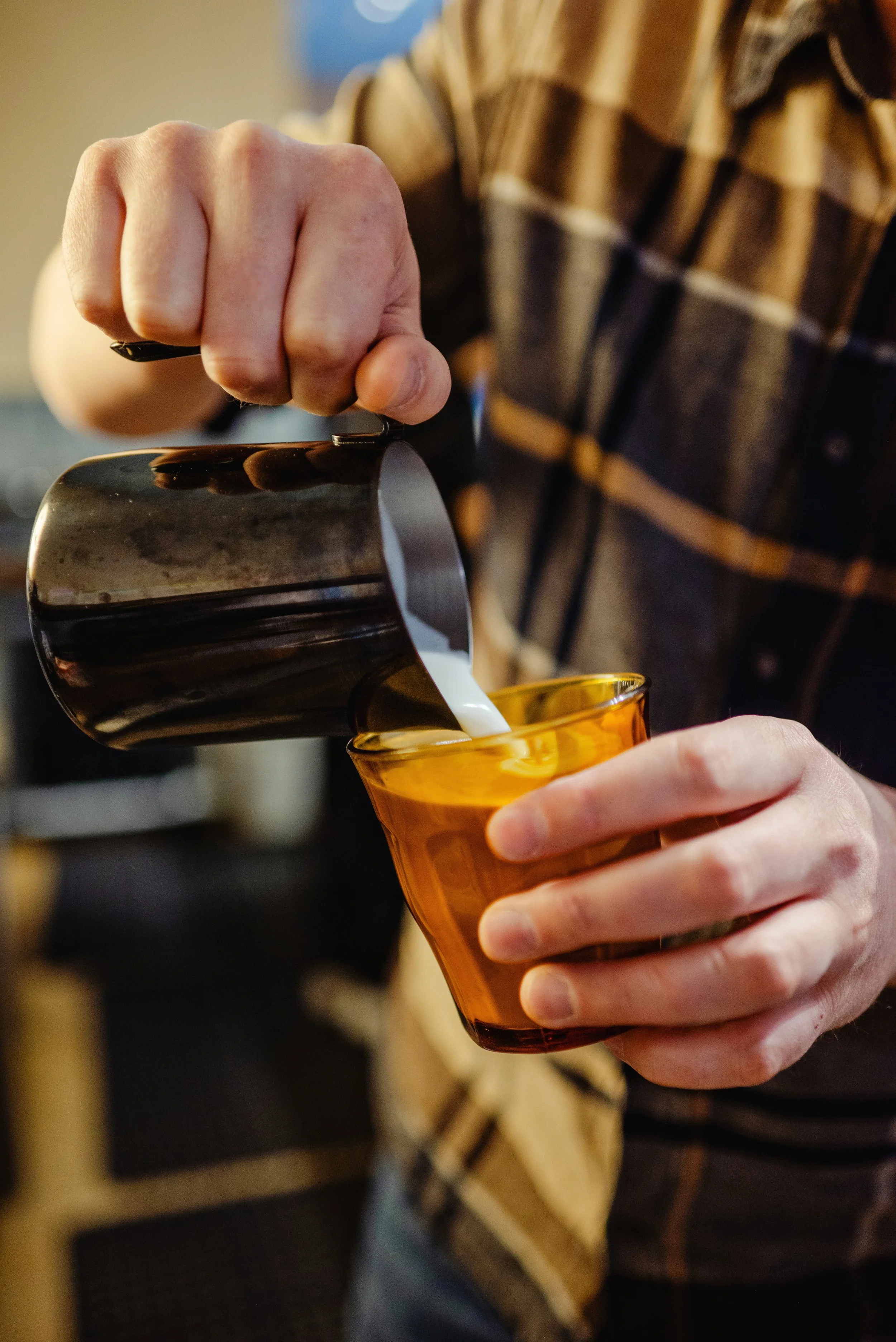 Photo of a barista pouring milk for latte art.