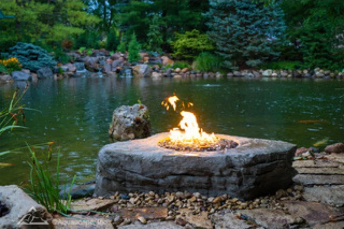 Custom stone fire pit beside a pond in Marion NC by Greenspan Landscaping Company