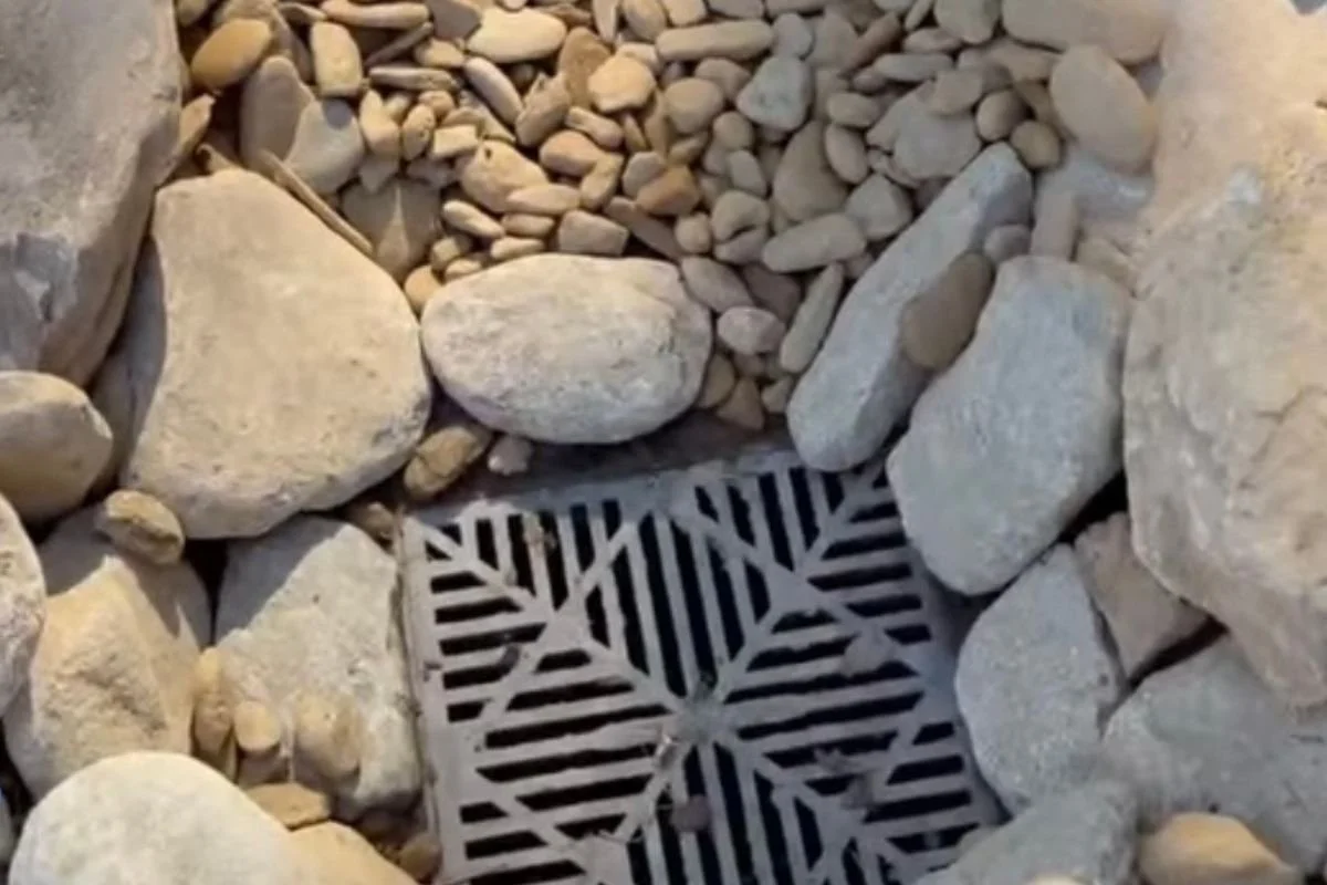 Close-up of box drain installed in stone-lined drainage system to redirect water away from foundation in Black Mountain North Carolina