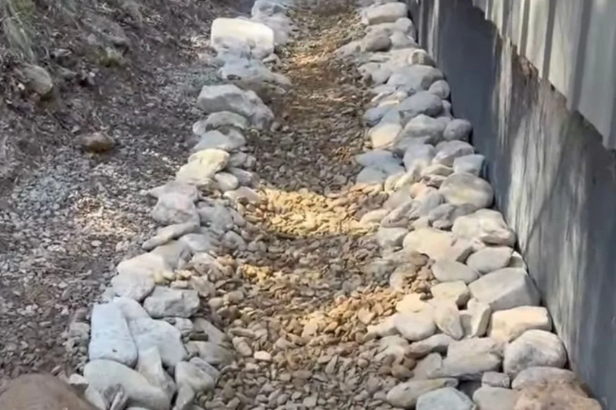 Stone-lined drainage swale and box drain system directing water away from foundation in Black Mountain North Carolina