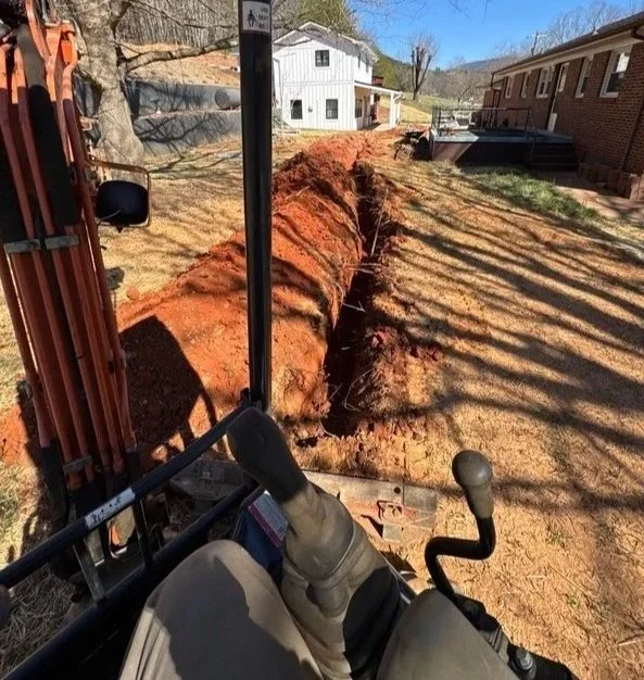 Excavation of drainage trench to prevent water pressure behind retaining walls in Old Fort North Carolina