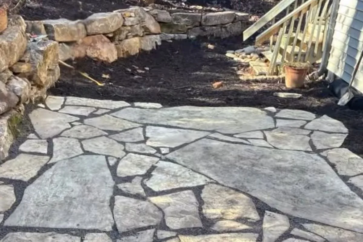 Flagstone patio with natural stone retaining wall in Asheville mountain backyard