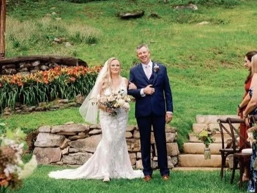 Stone retaining wall and cut stone steppers installed by Greenspan Landscaping Company in Black Mountain, NC. Elegant garden setting with lush green grass, blooming flowers, and professionally crafted hardscape design.