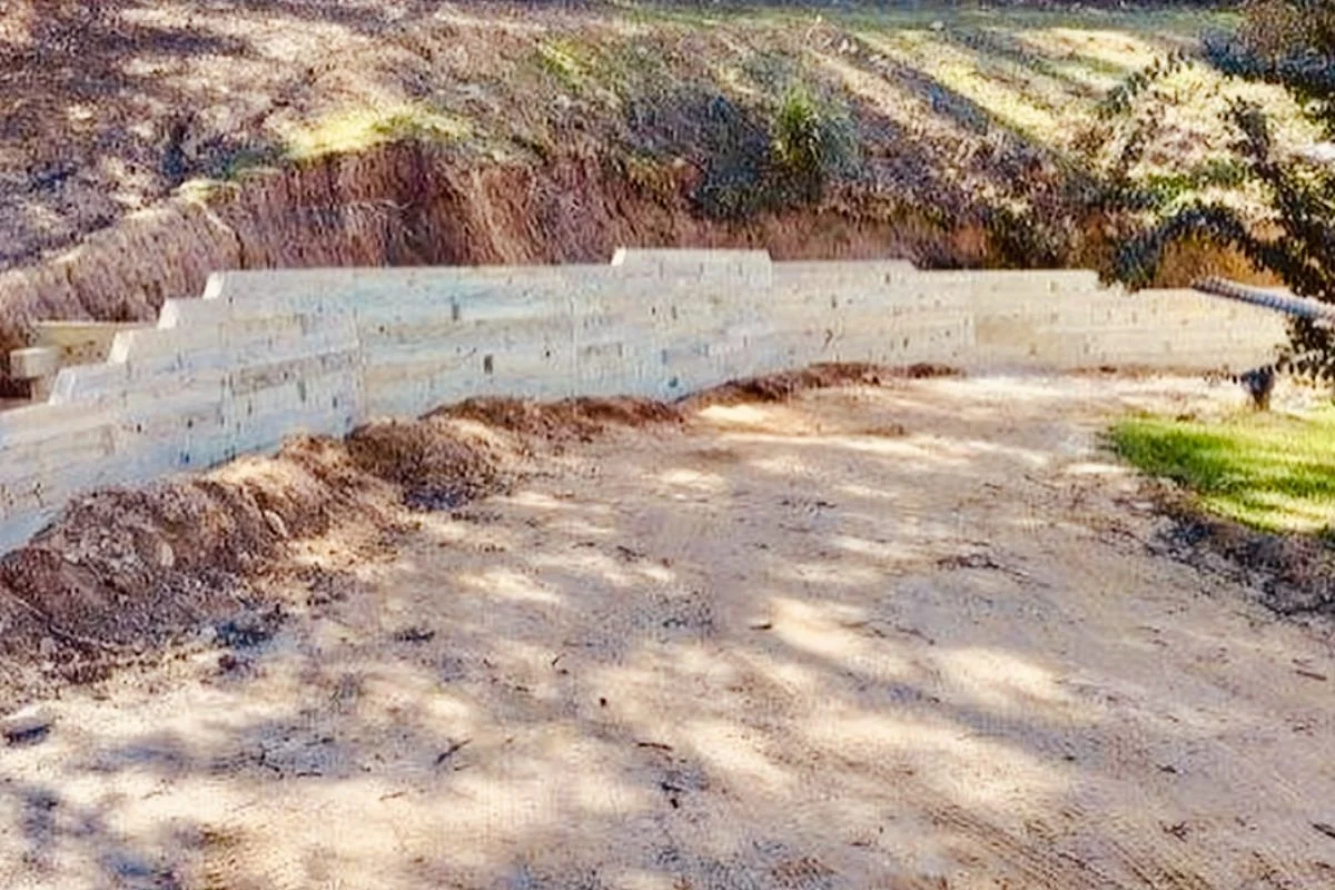 Front view of timber retaining wall wrapping around property with soil for landscaping design by Greenspan Landscaping in Black Mountain, NC.