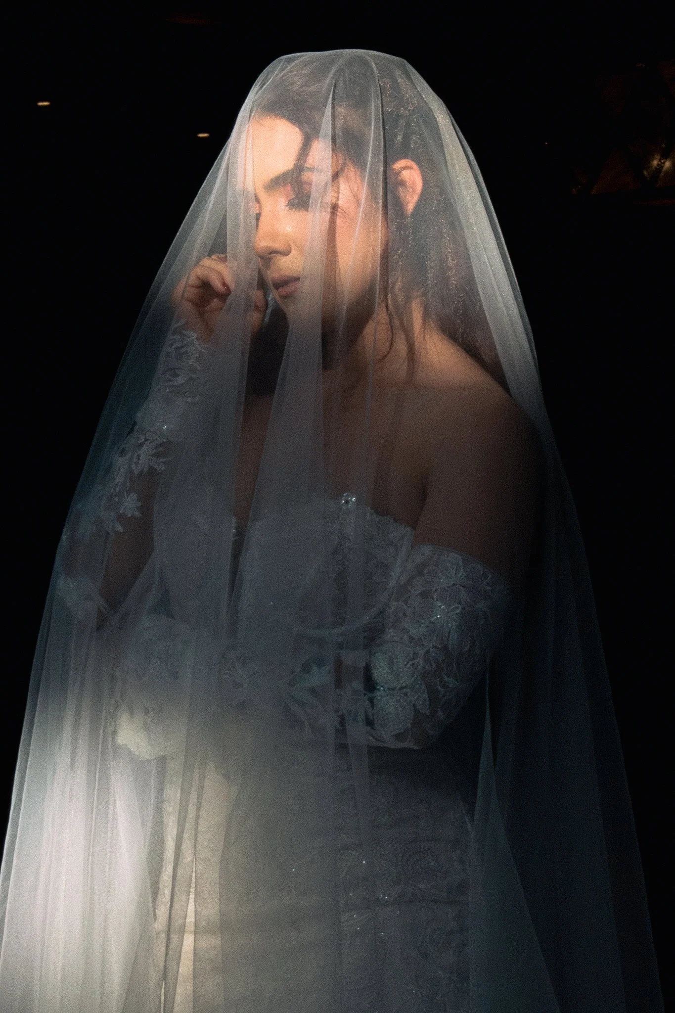 Una mujer vestida con un vestido de novia y un velo, en un entorno oscuro