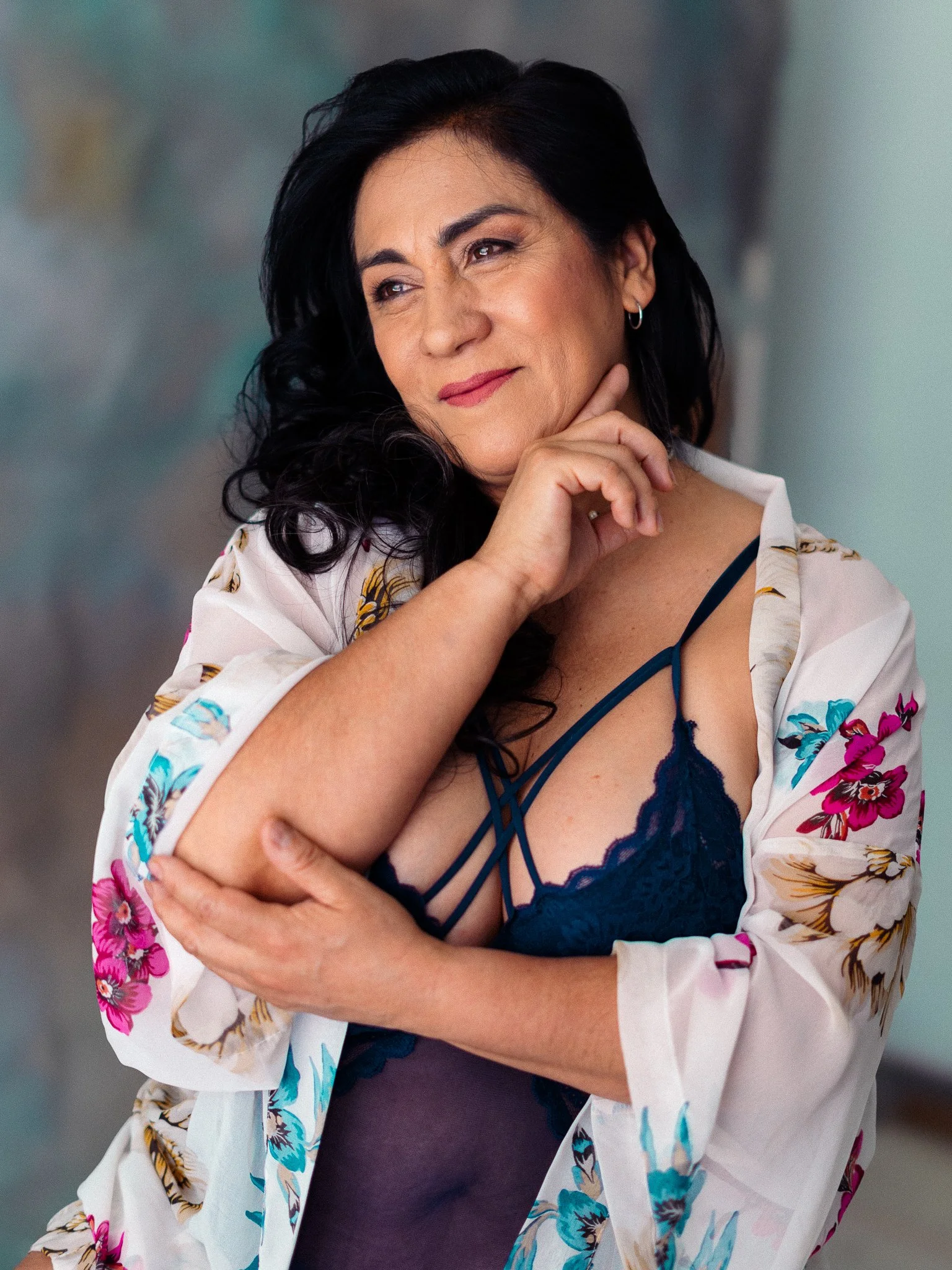 Mujer con cabello negro, vestida con un camisón azul y bata con flores dichosa en un entorno interior
