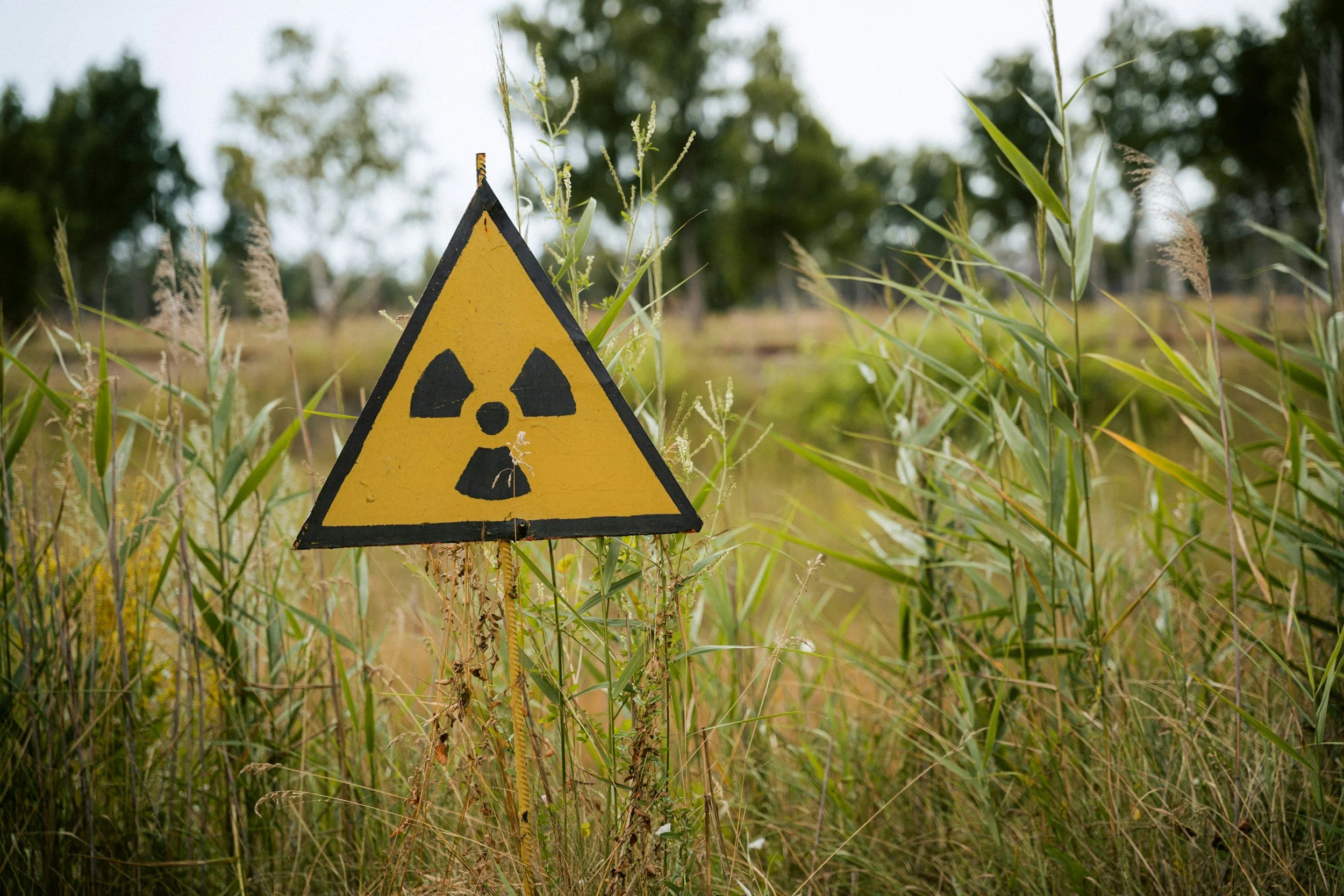 Radioactive warning sign in an overgrown field, representing Iran's nuclear program suspension claims analyzed in this strategic intelligence report on the Iran war diplomatic pivot