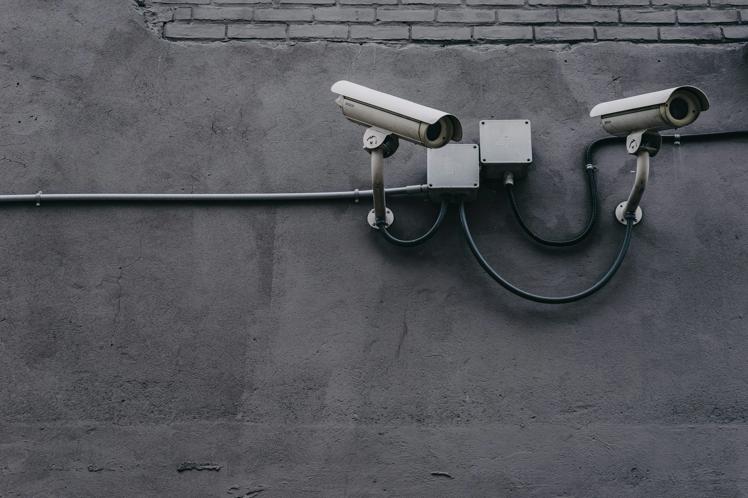 Two surveillance cameras mounted on a concrete wall — physical security assessment