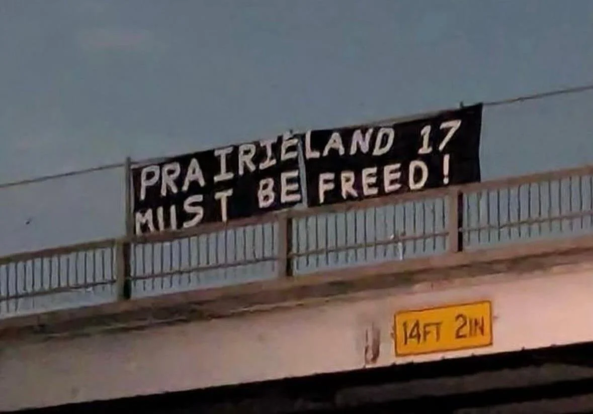 Banner referencing the “Prairieland 17” displayed above a roadway amid a domestic extremism investigation linked to an attack on a Texas ICE facility