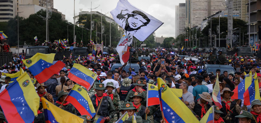 Large crowd of demonstrators carrying Venezuelan flags during a protest in an urban street