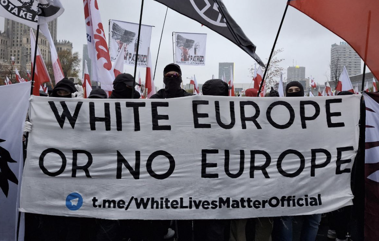 Masked demonstrators holding a banner reading ‘White Europe or No Europe’ during a public protest