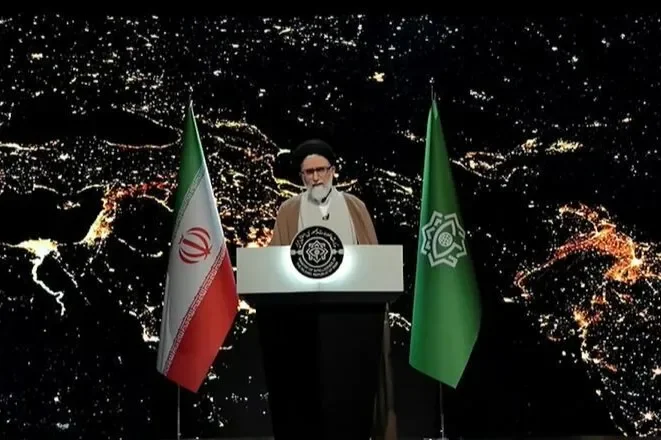 Iran’s Supreme Leader speaks at a podium flanked by Iranian flags against a nighttime city backdrop