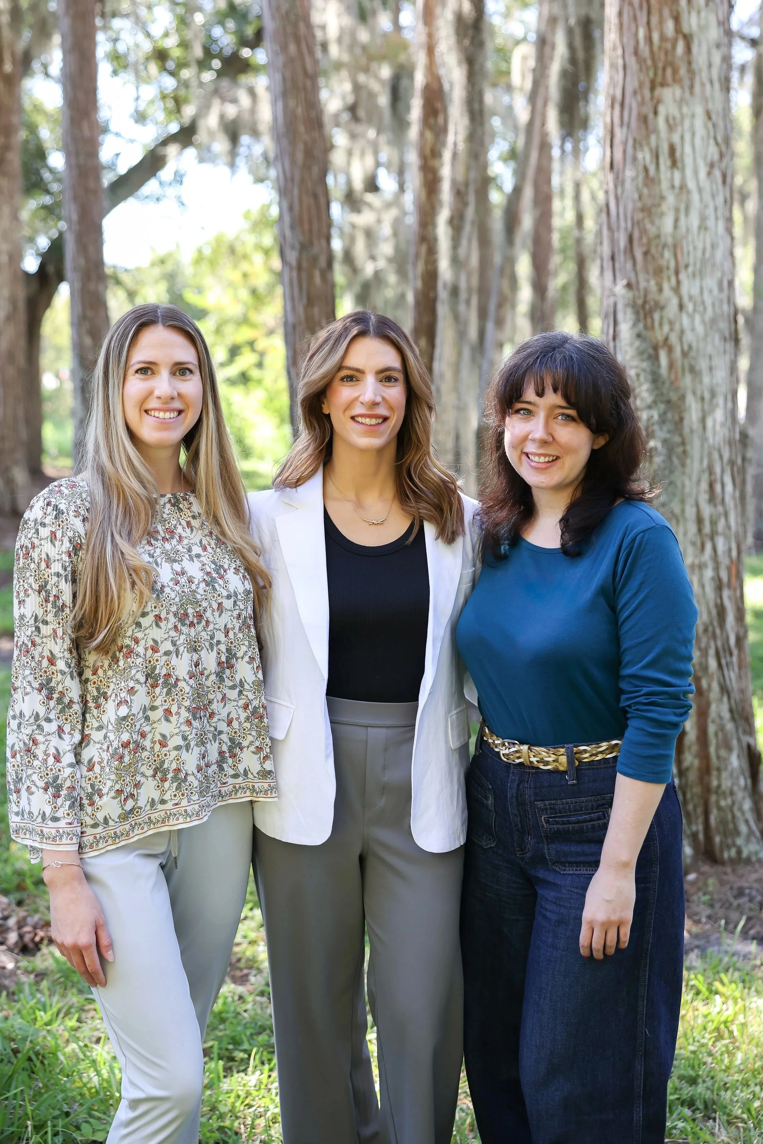 Intuitive Therapies & Pelvic Health Team in Tampa, FL standing outdoors in a green wooded area, smiling at the camera. Physical and Occupational Pelvic Floor Therapy in Tampa.
