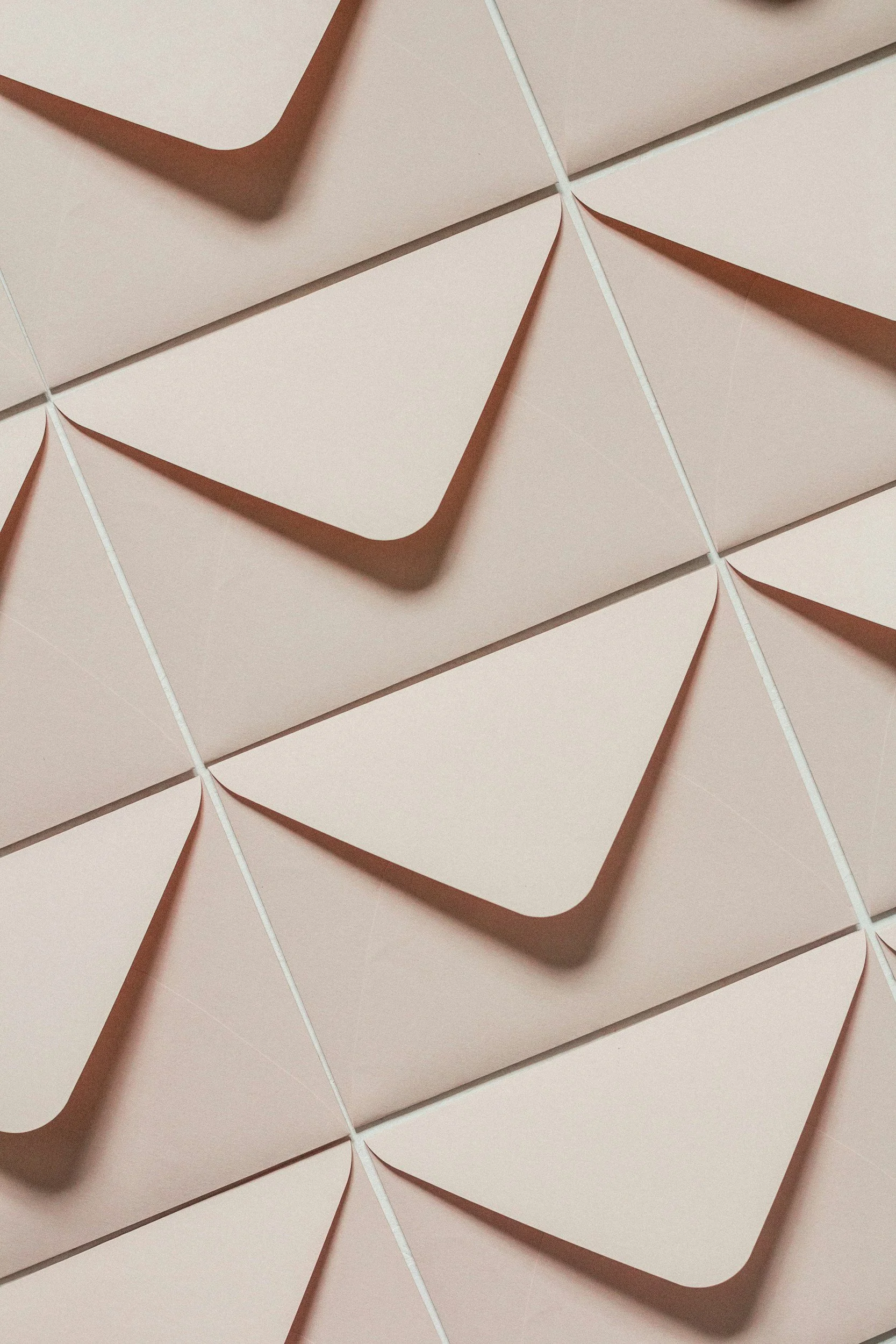 Close-up of pink square boxes with rounded corners and a cutout triangle on the front, topped with white strings.