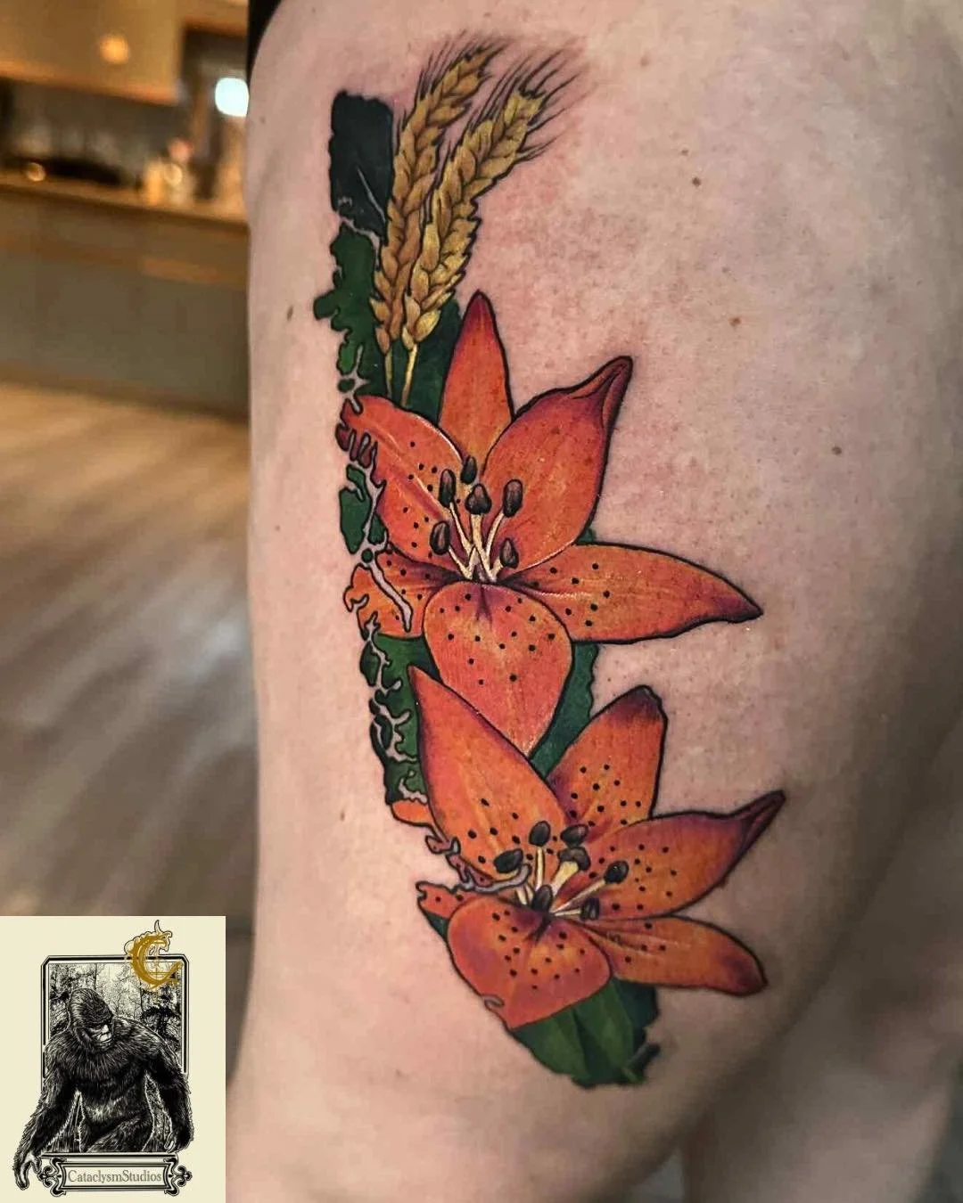 Tattoo of orange lilies with green leaves and wheat stalks on person's arm.