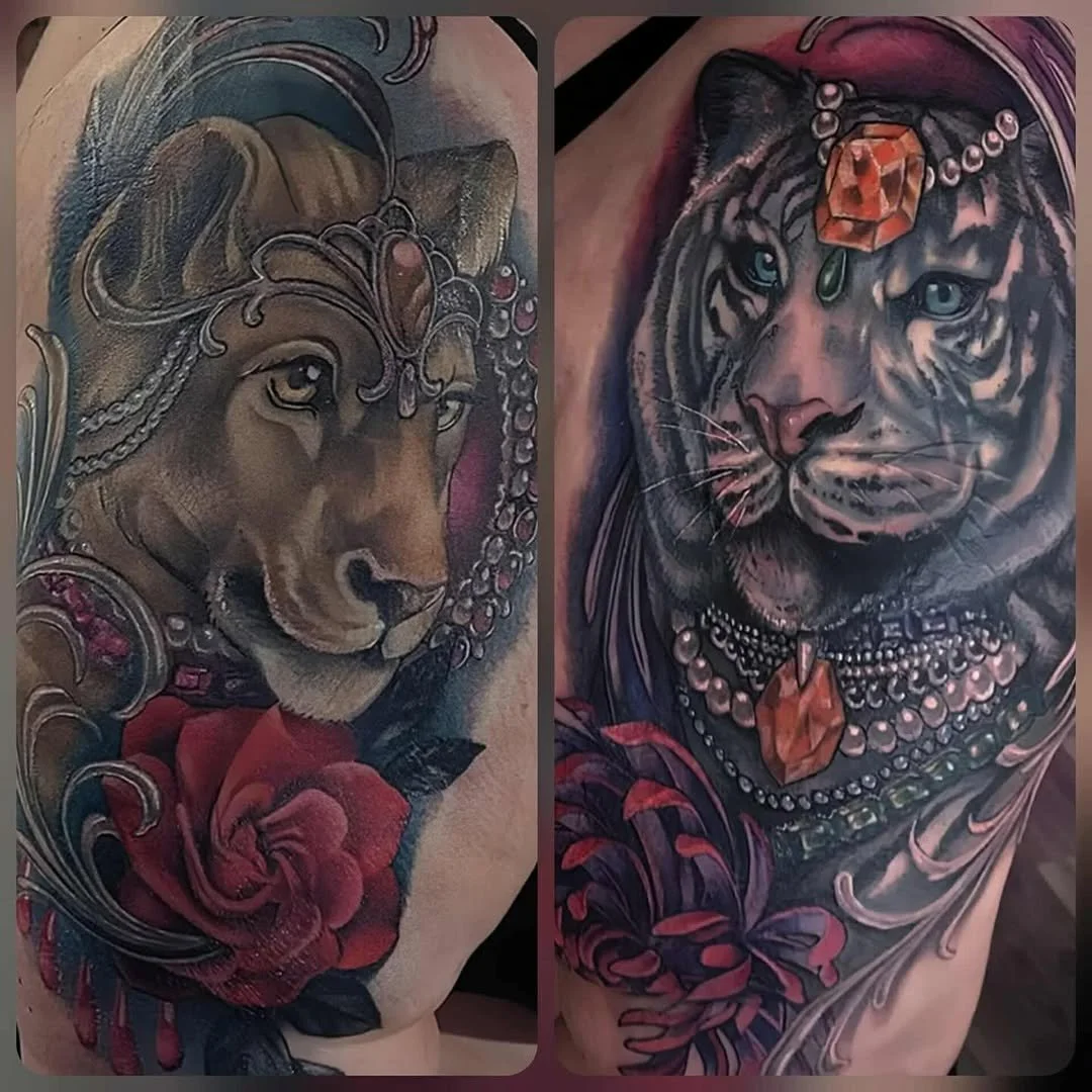 Tattoo of a lion wearing jewelry and accessories with a red rose below, and a tattoo of a tiger with jewelry and a large orange gemstone on its forehead and chest, surrounded by floral and decorative elements.