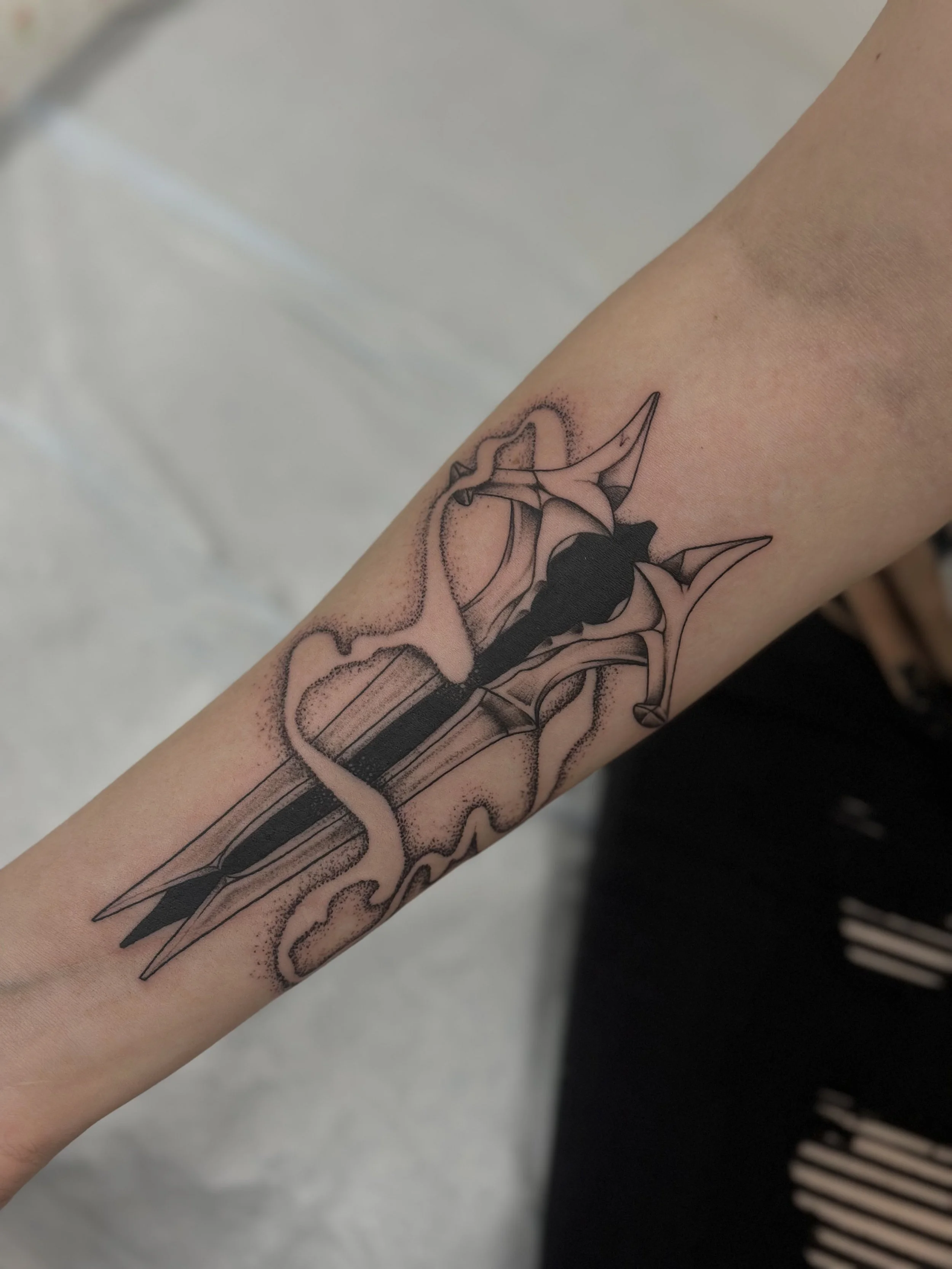 Tattoo of a sword intertwined with a snake, depicted in black ink with shading and dot work details.