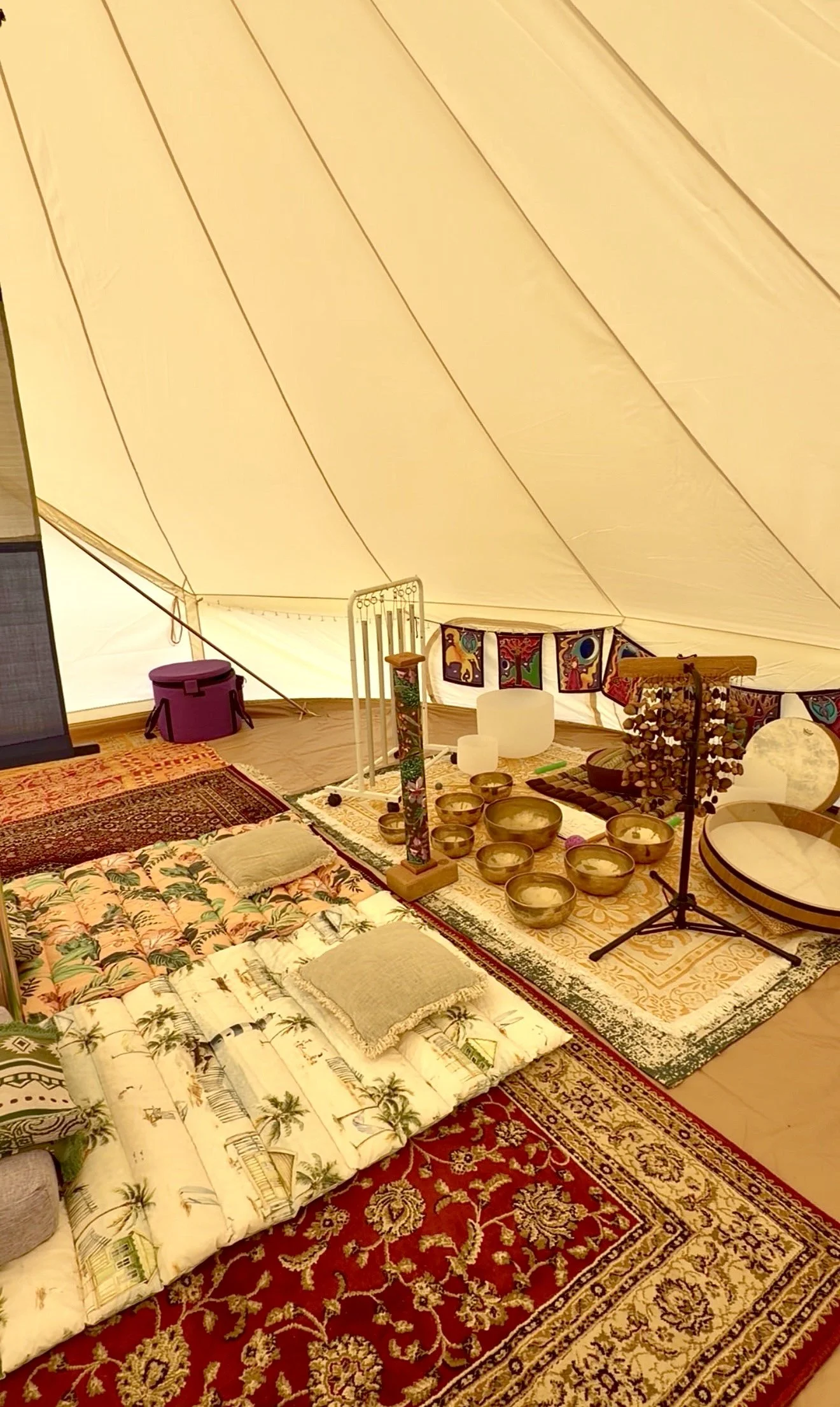 Absolutely beautiful place, back to nature in the glamping tent, sound healing, nervous system reset, relaxation, sound bath. There are singing bowls, a drum, and musical instruments arranged on the floor, creating a cosy, artistic space.