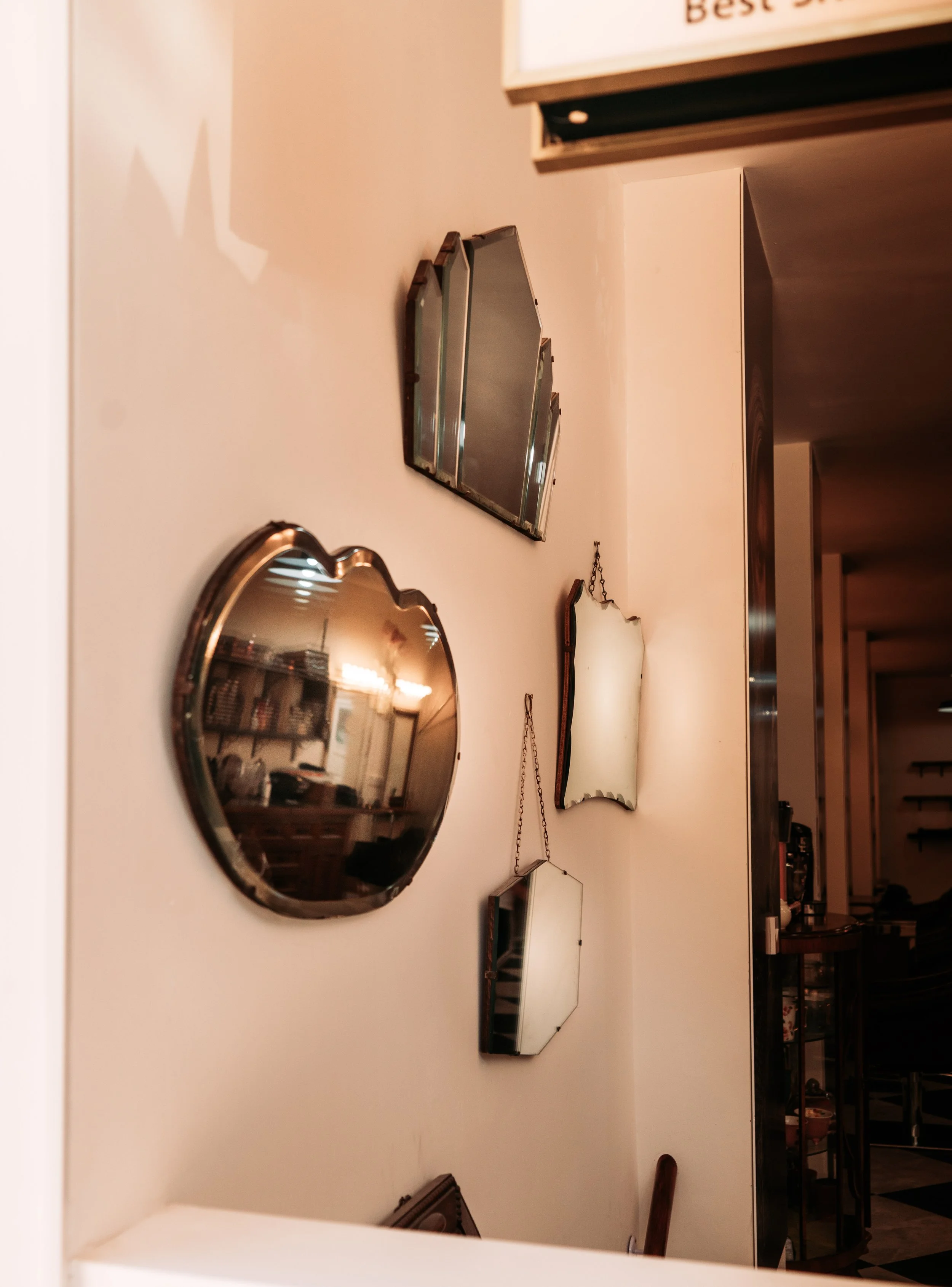 Collection of decorative mirrors of various shapes and sizes on a white wall in a cozy interior space.