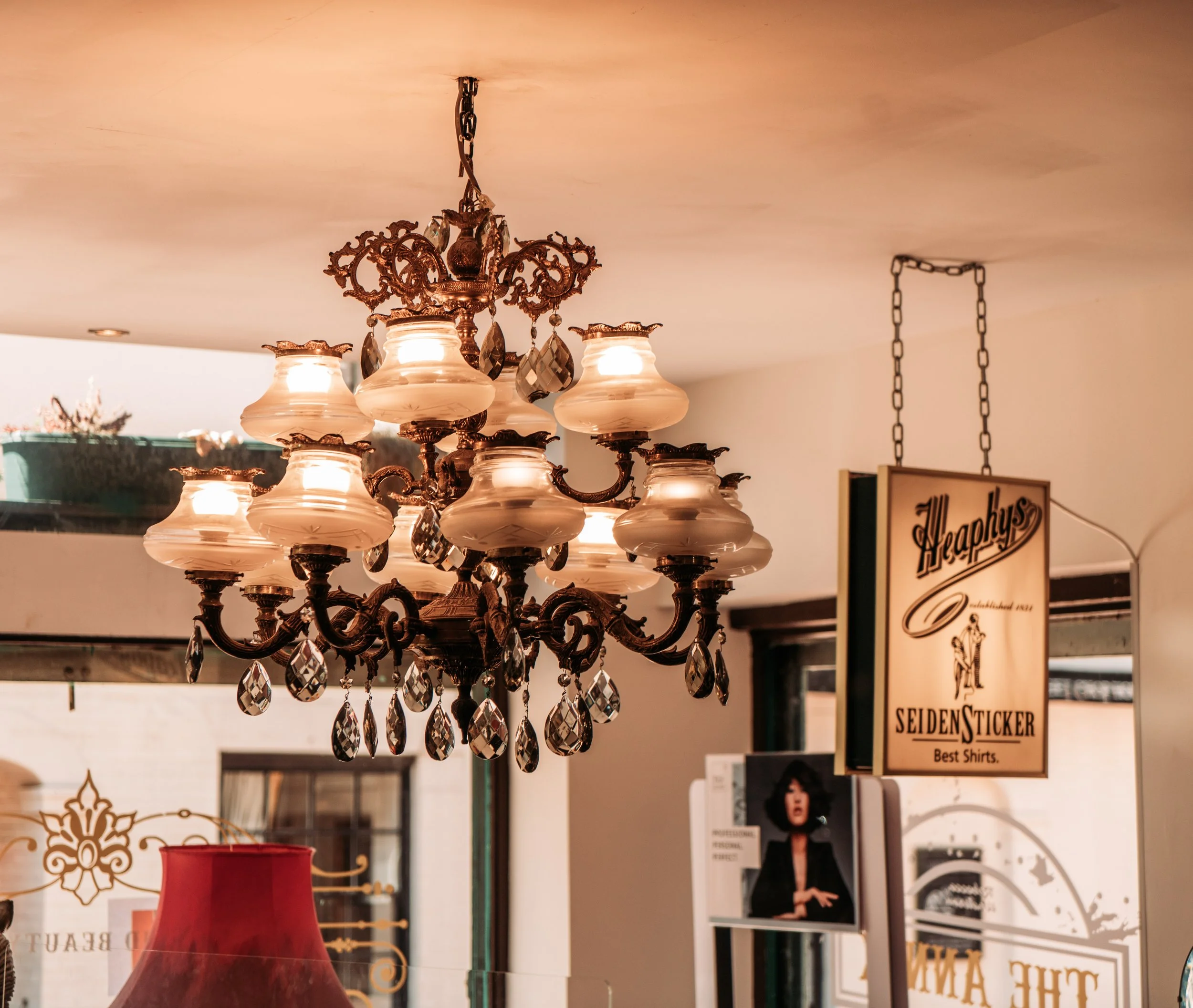 A vintage chandelier with multiple glass lampshades and crystal accents hanging from a ceiling.