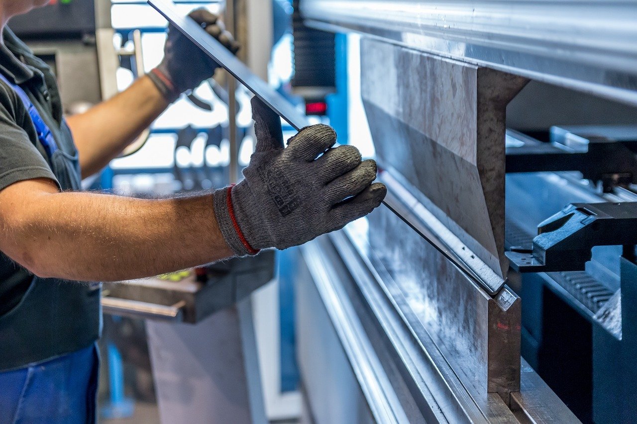 Worker cutting a piece of stone with a handheld power saw in a workshop.