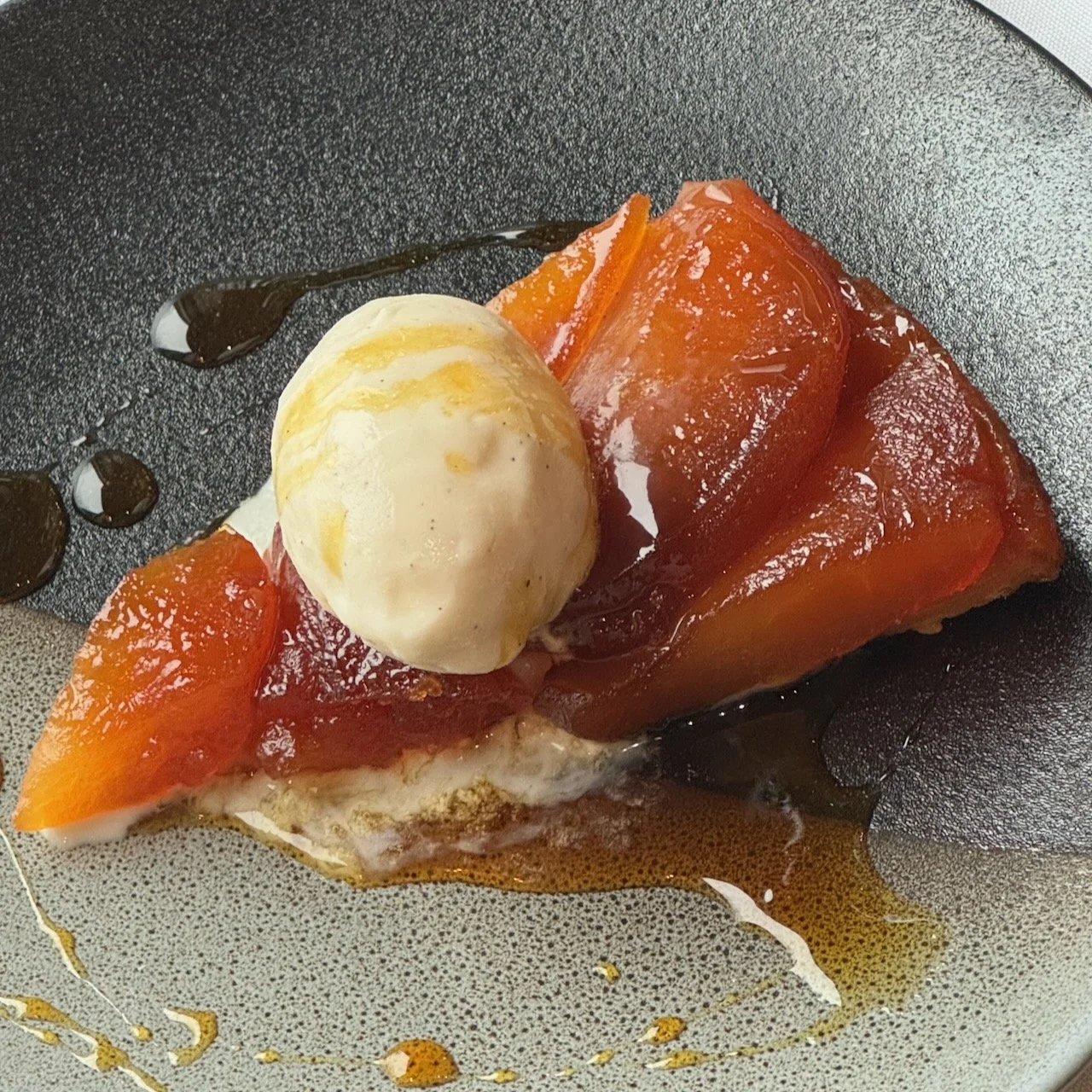 Tarte Tatin with ice cream on dark plate